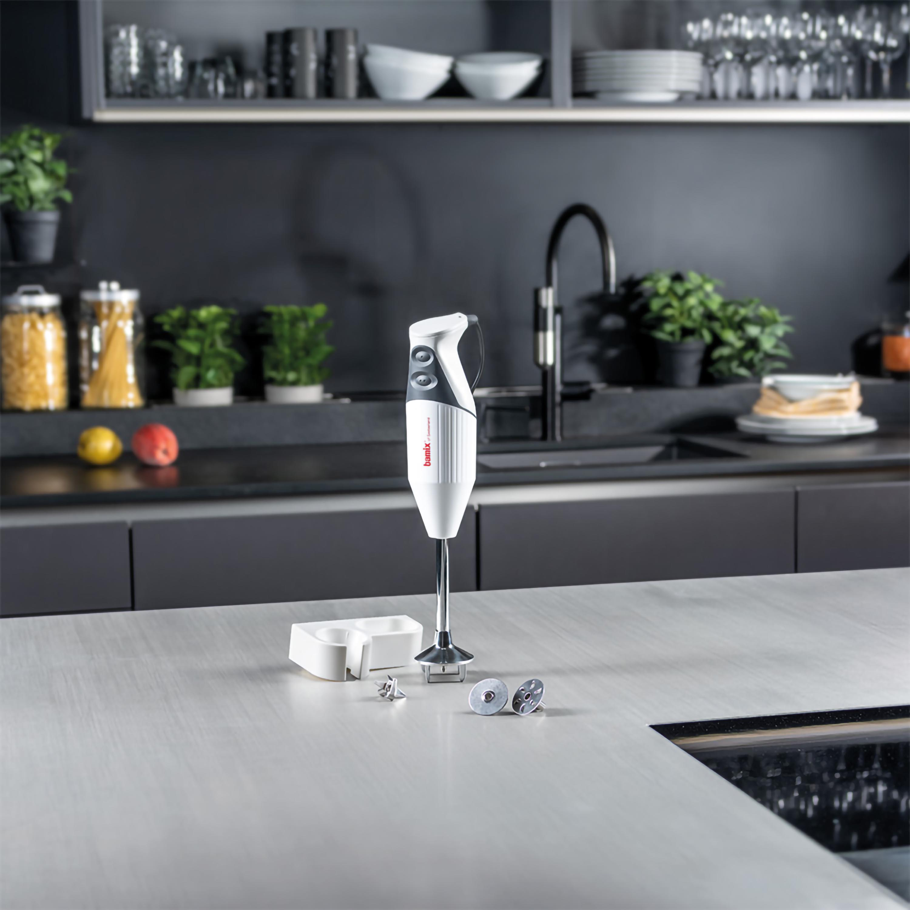 Frullatore a immersione bianco con accessori su un piano cucina.