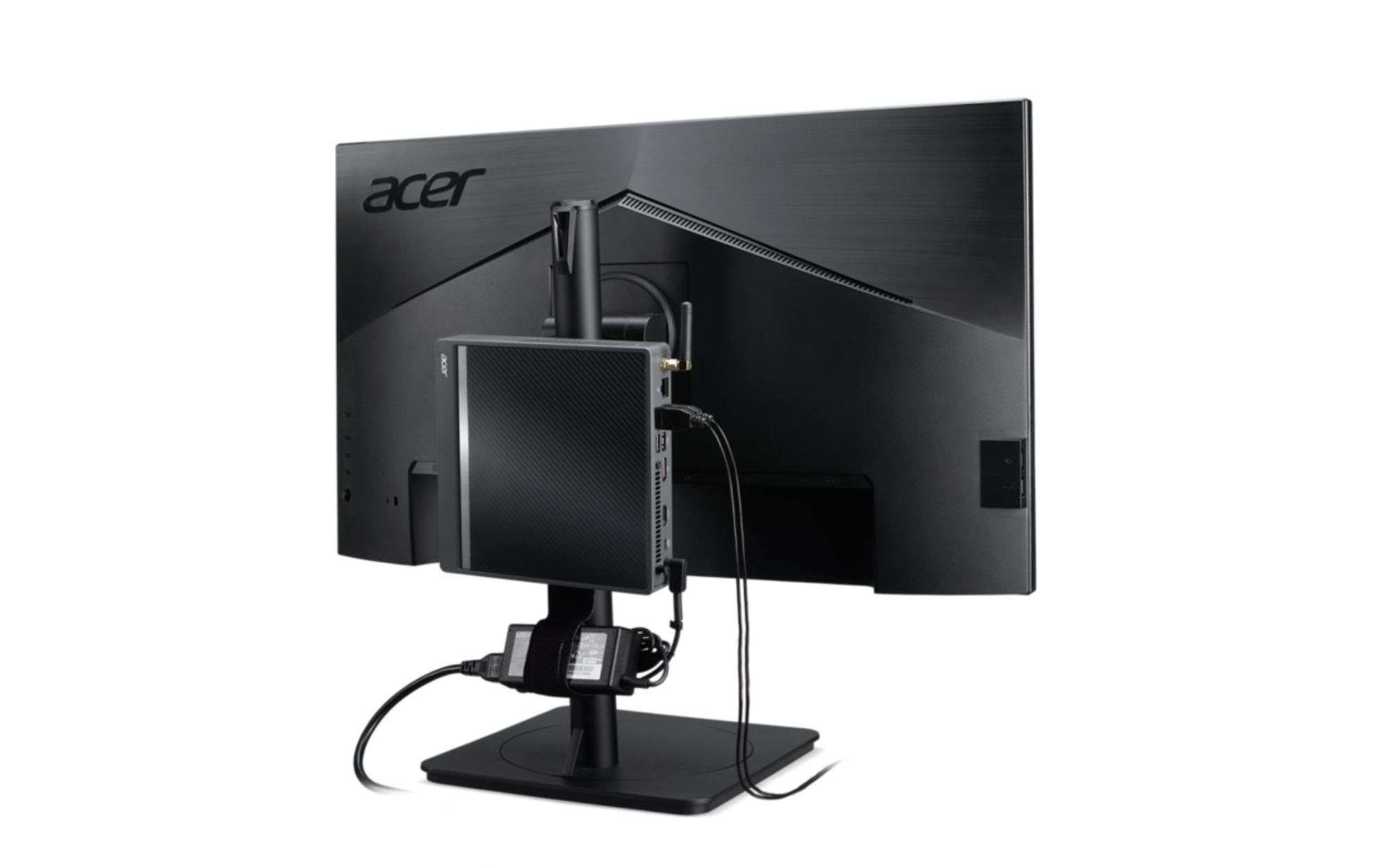 Vista posteriore di un monitor per computer con un mini PC collegato, isolato su bianco.