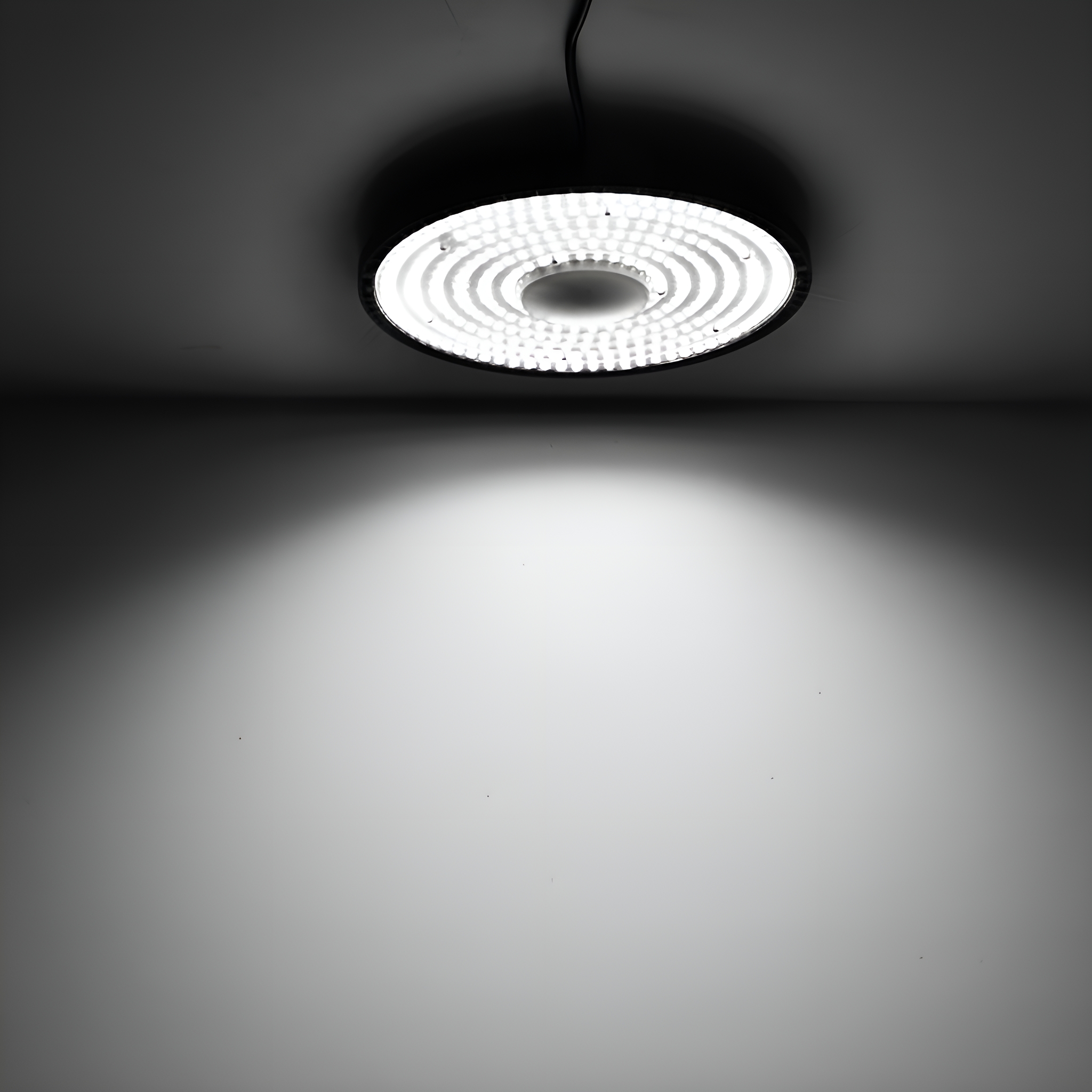 Kreisförmige LED-Panel-Leuchte, von der Decke hängend, wirft weißes Licht auf eine weiße Wand darunter.