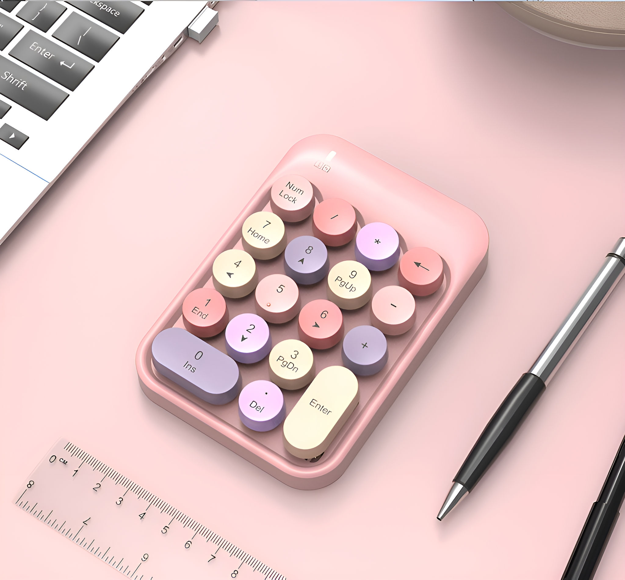 Ein rosa numerischer Ziffernblock mit bunten runden Tasten, ein Lineal, ein Stift und ein Laptop.