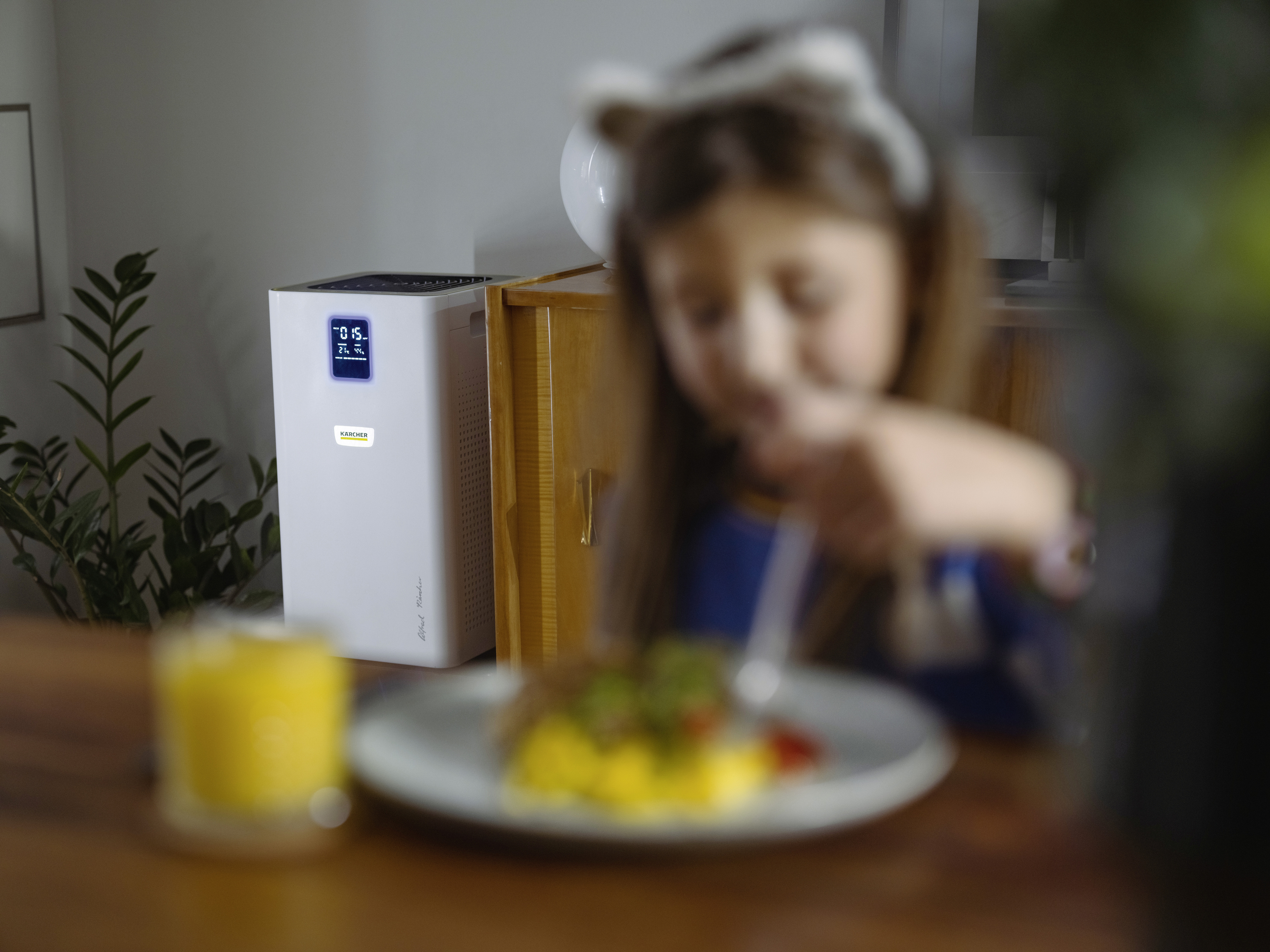 A child eating near a table with food. An air purifier is on the left.