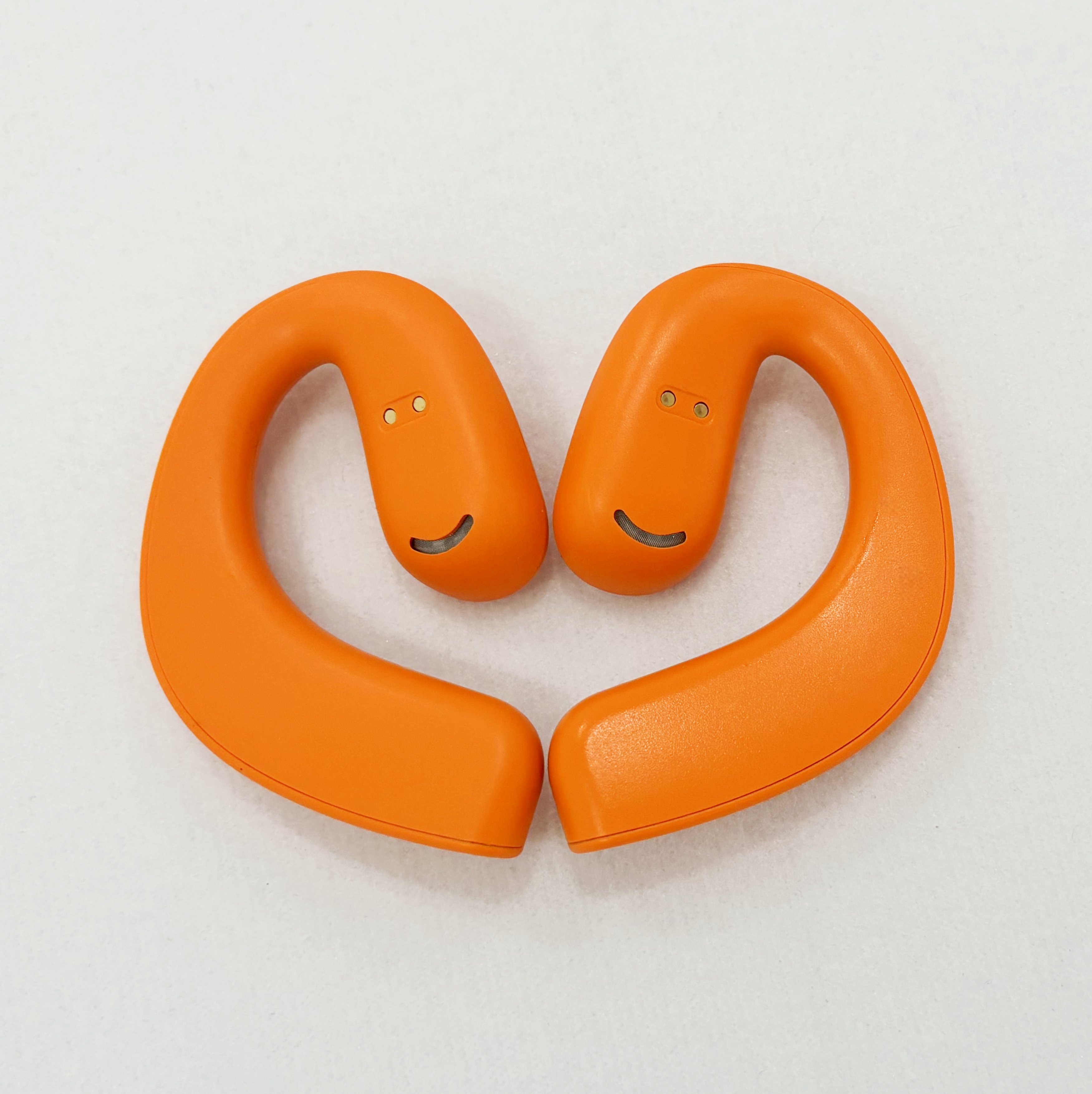 Dos auriculares de diadema naranja con caras sonrientes, sobre una superficie blanca.