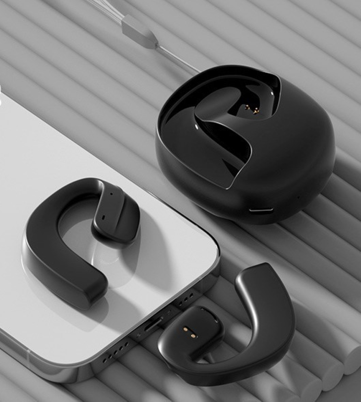 Auriculares inalámbricos negros y su estuche de carga sobre un teléfono blanco. Los auriculares son en U.