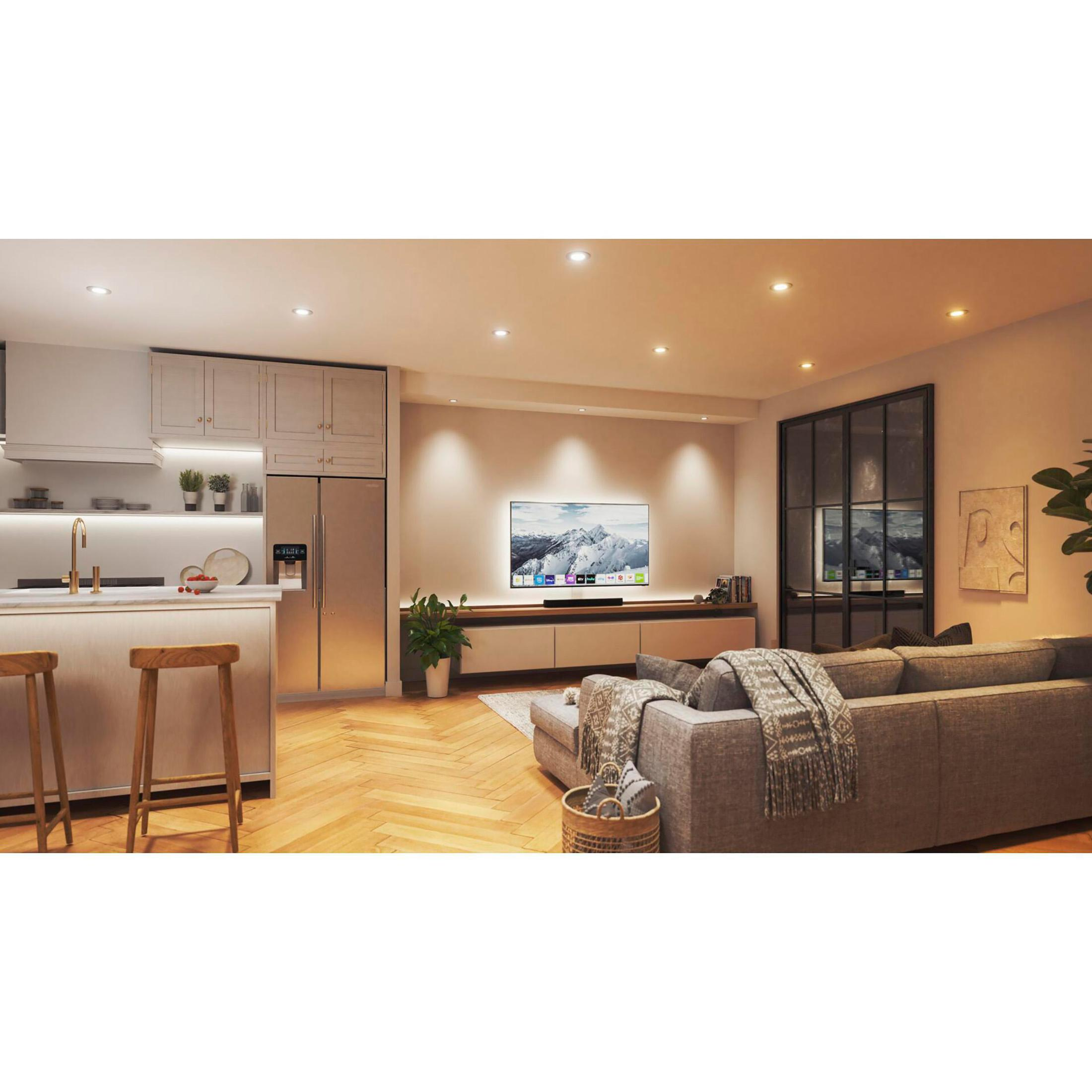 Un soggiorno moderno con TV, divano grigio, pavimenti in legno e luci a soffitto luminose.