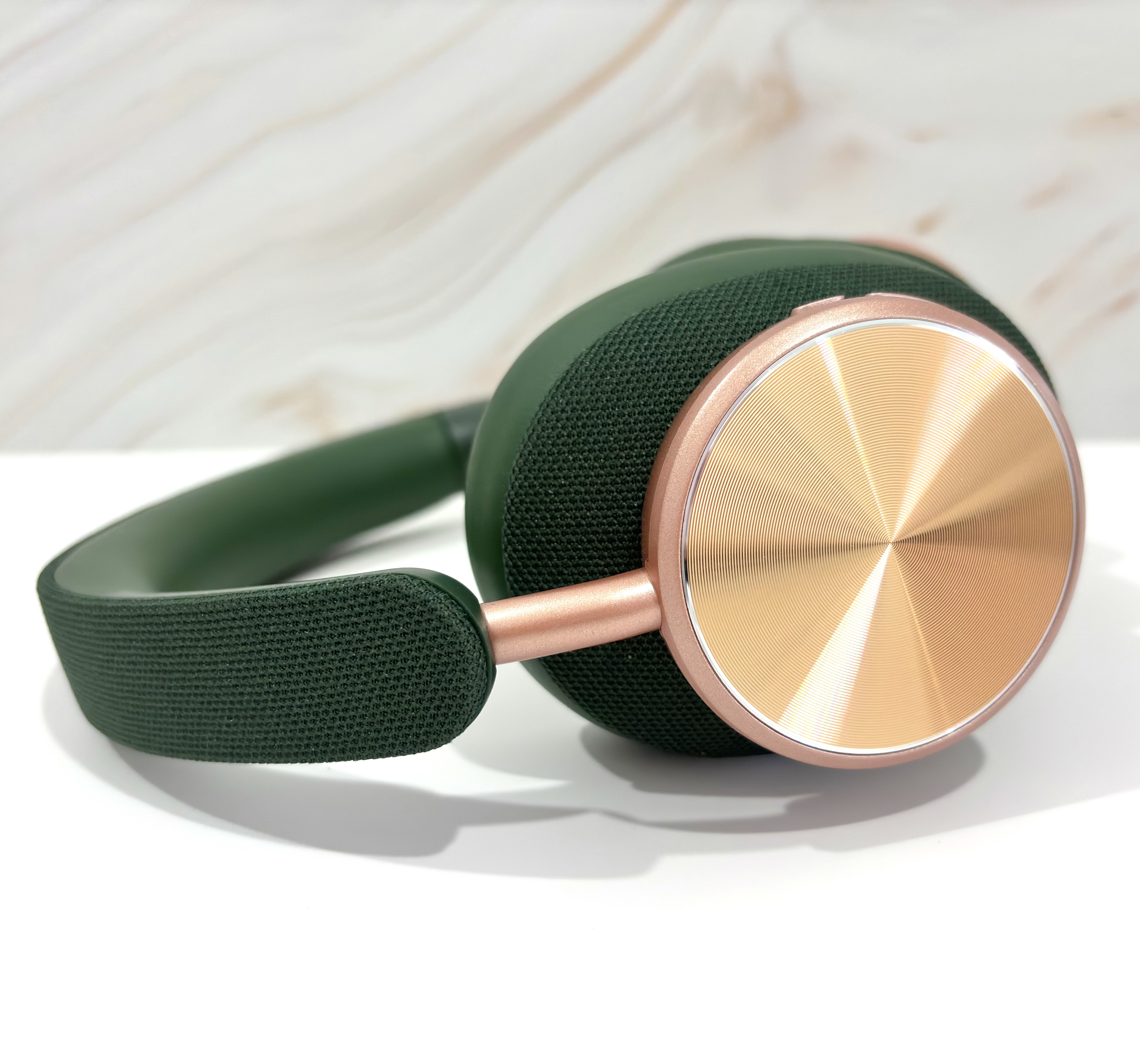 Auriculares verdes y dorados sobre una superficie blanca. Fondo de mármol.
