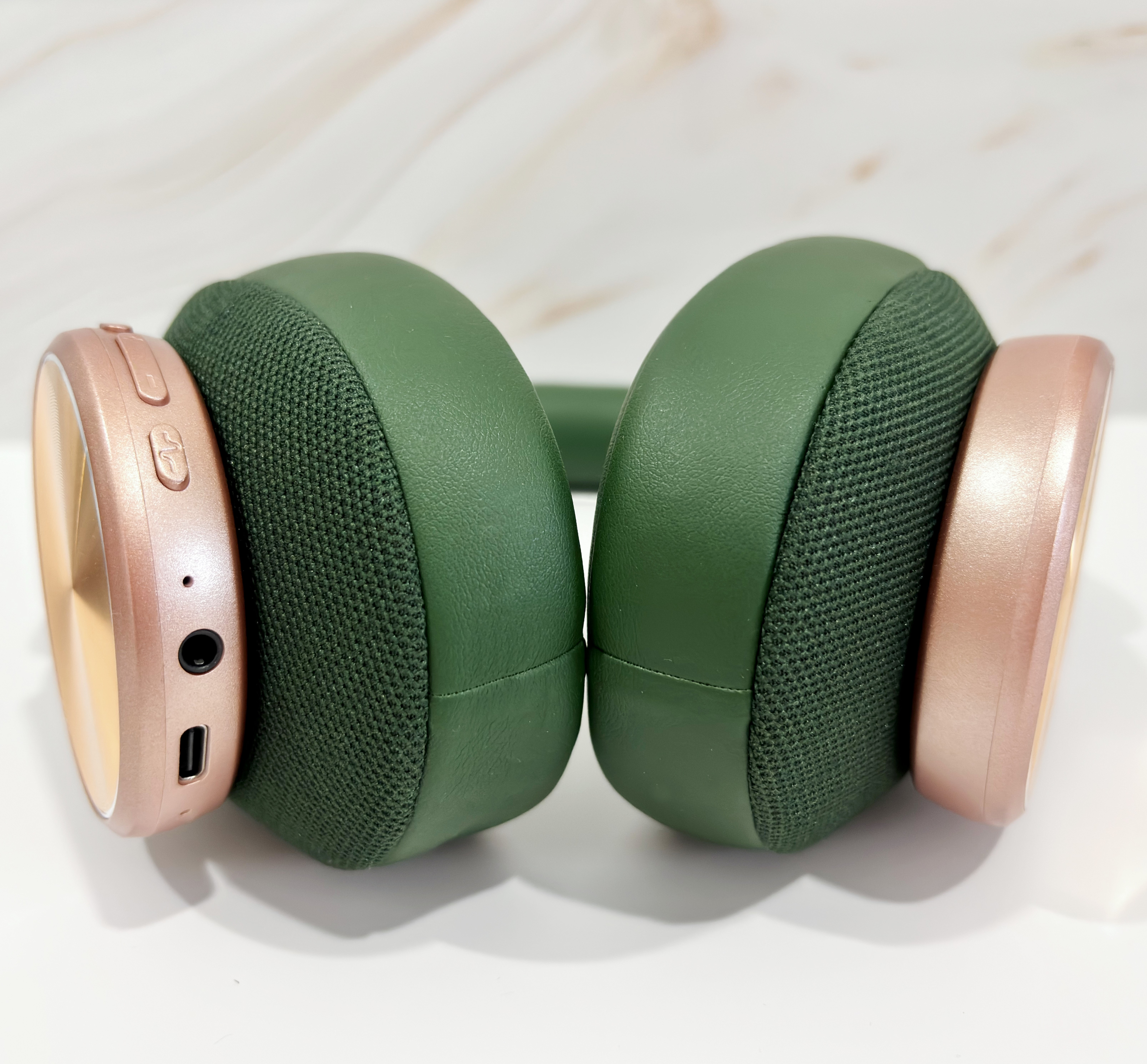 Auriculares verdes y oro rosa. Cada auricular tiene un lado de oro rosa y una almohadilla verde.