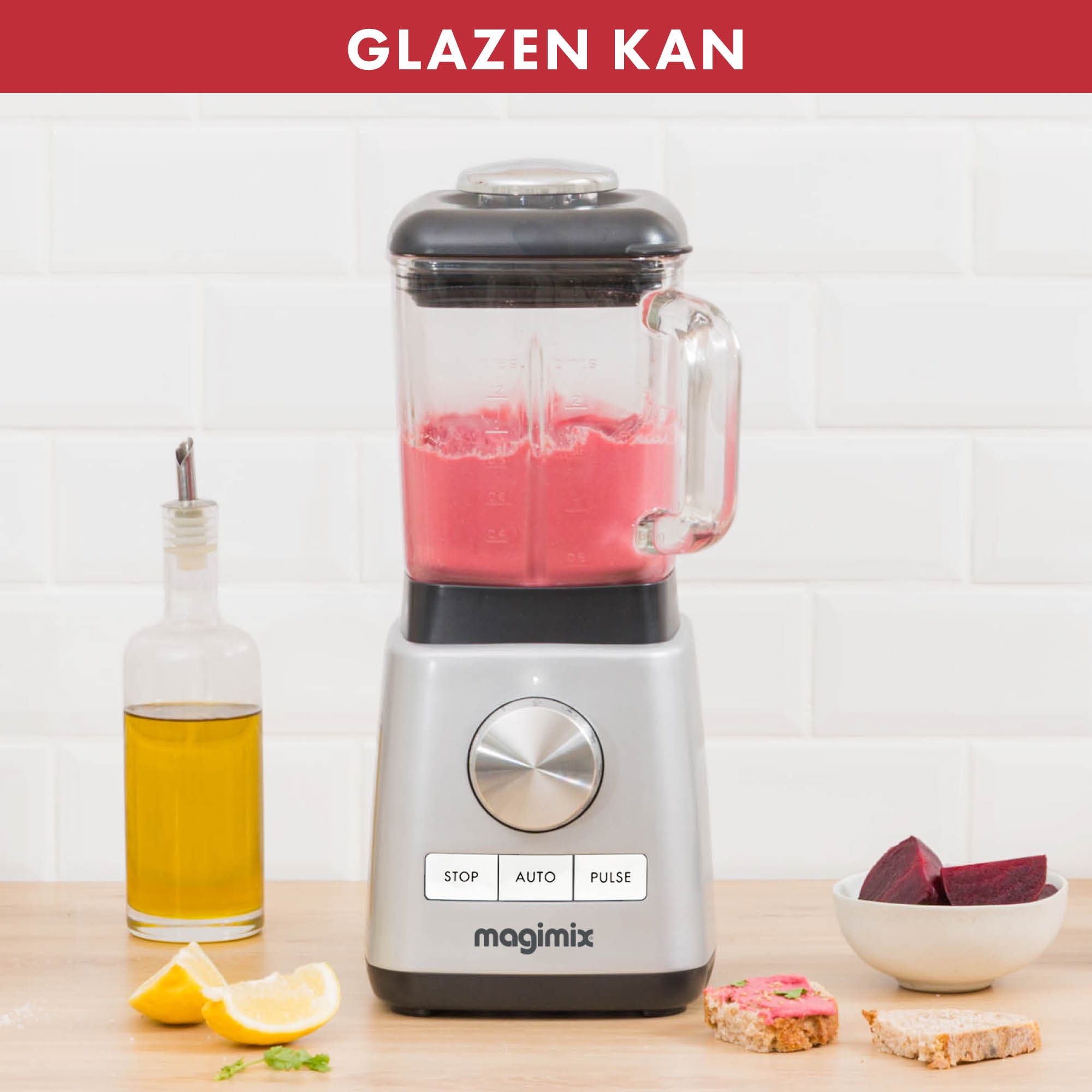 Blender met rode vloeistof, citroenen en bieten op een houten tafel. Witte tegelmuur.