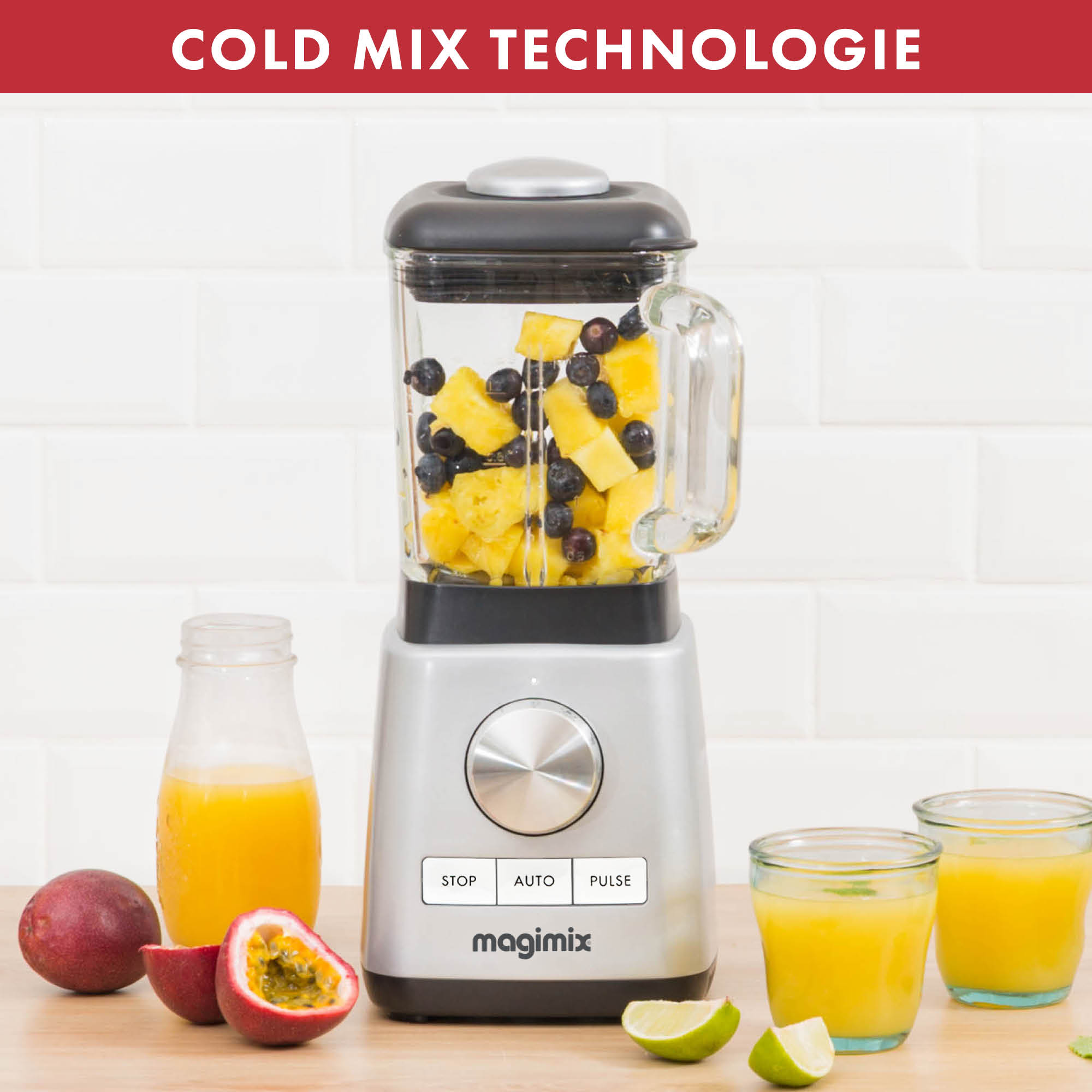 Een blender met fruit erin, met passievrucht en sapglazen op tafel.