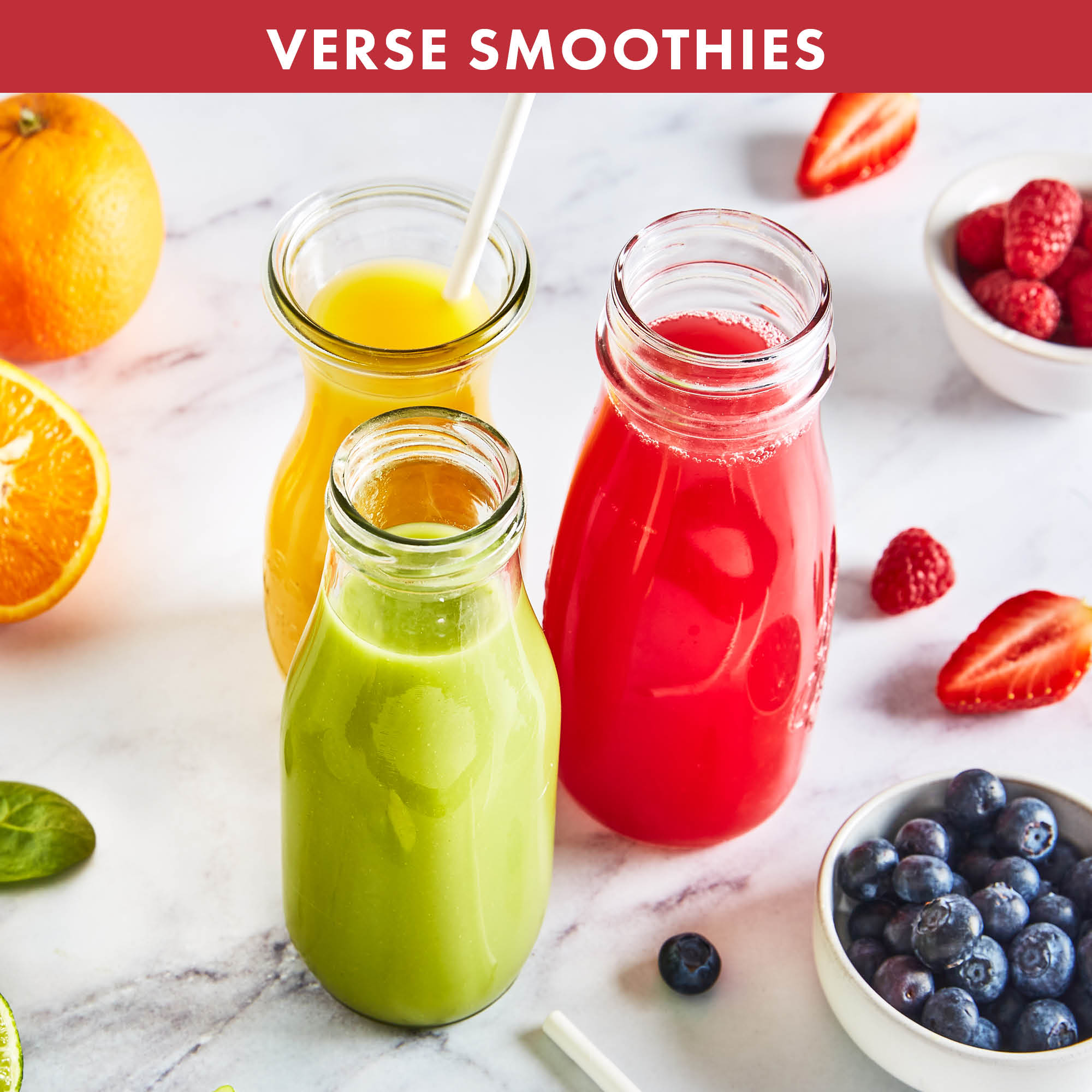 Drie smoothies in glazen flessen, oranje, geel en rood, met fruit eromheen.