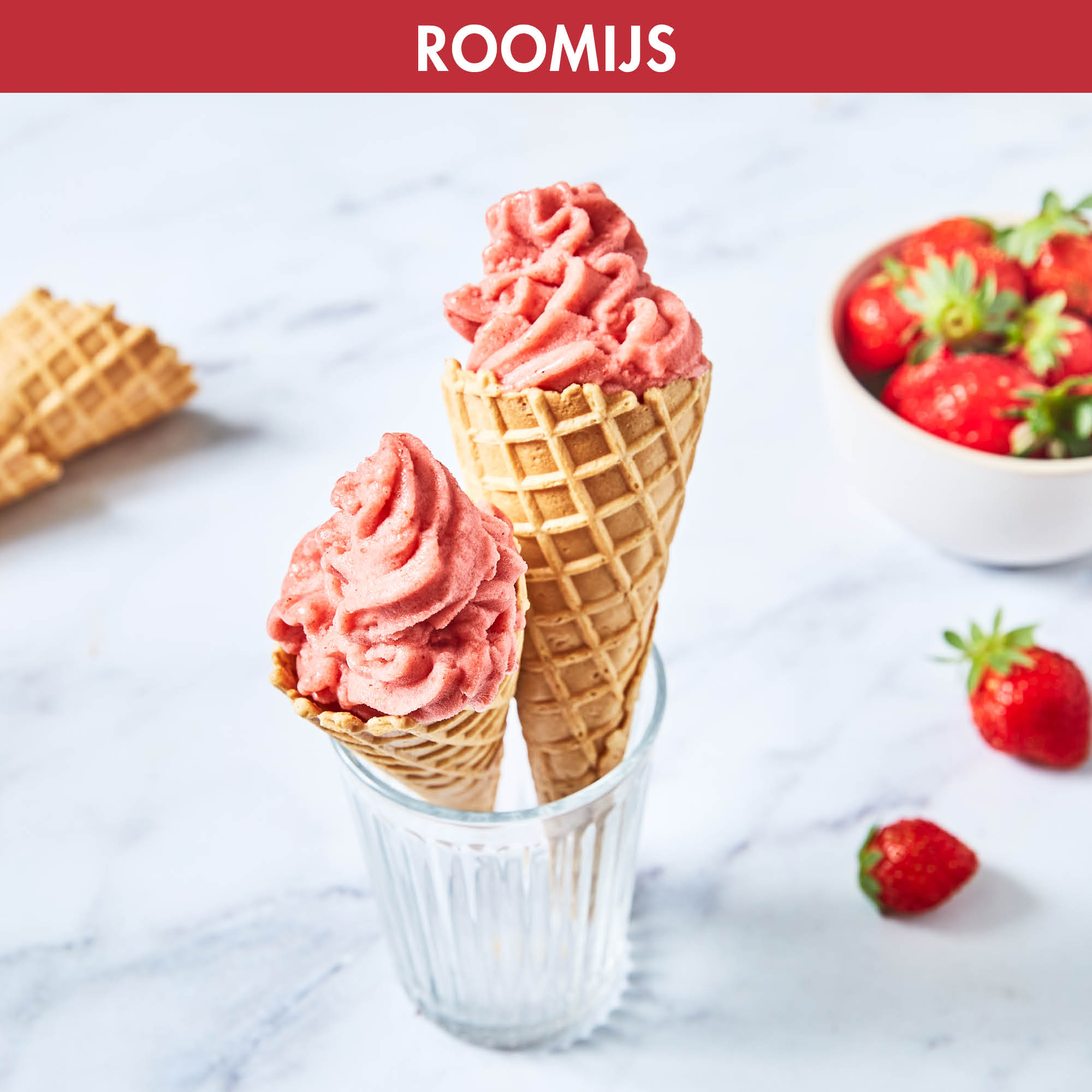 Two ice cream cones with pink ice cream. Strawberries are in a glass and some are on the table.