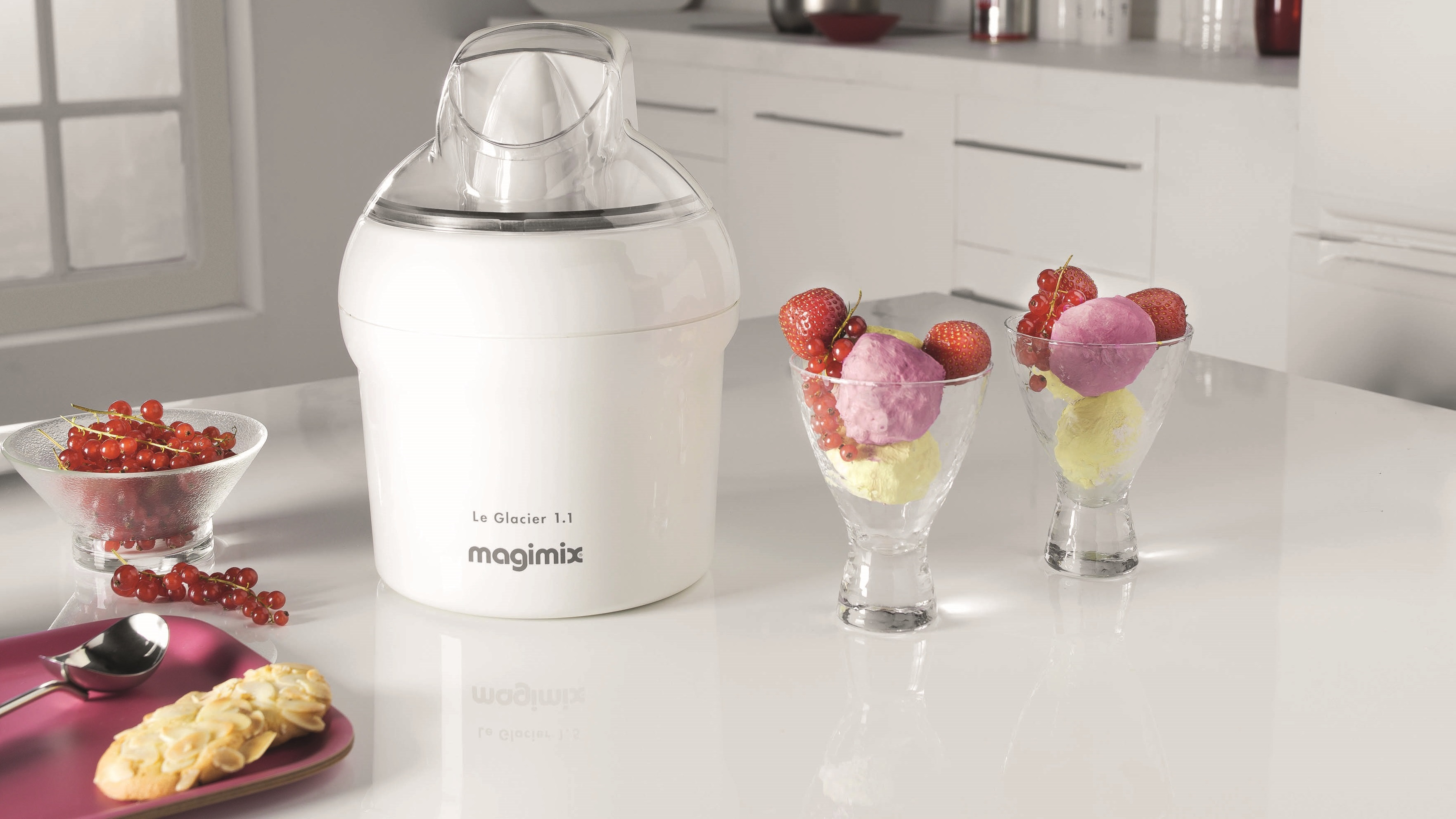 Ice cream maker with ice cream in cups, and berries.