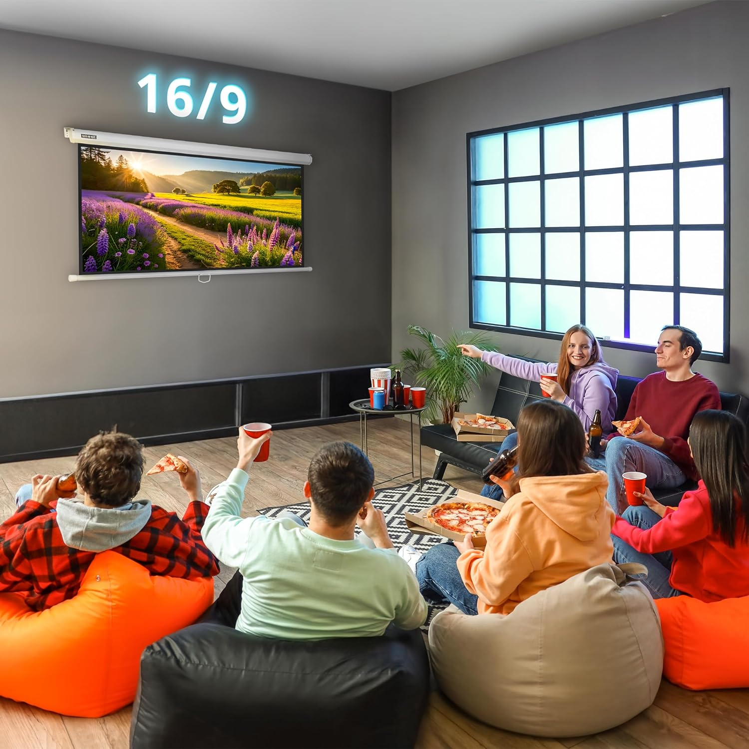 Grupo de personas viendo una pantalla, comiendo pizza y bebiendo. La habitación es oscura.