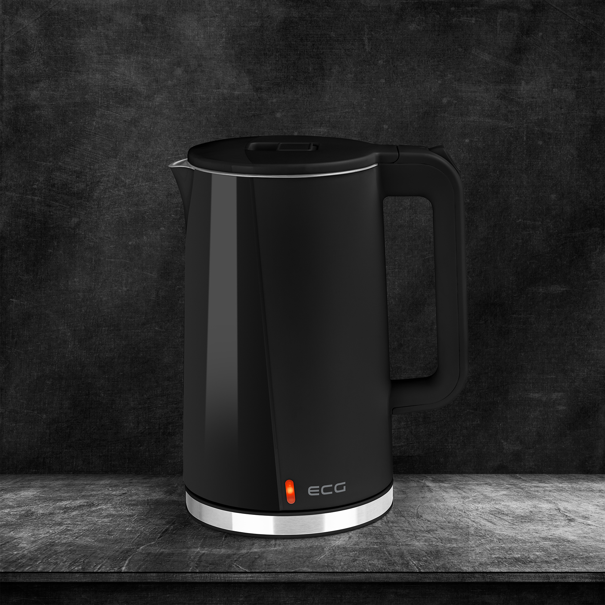Bollitore elettrico nero con manico e luce rossa su superficie grigio scuro.