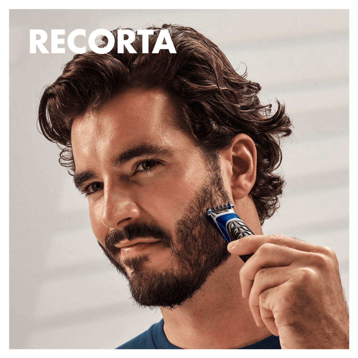 Hombre recortando su barba con una afeitadora eléctrica. Texto en español superpuesto.