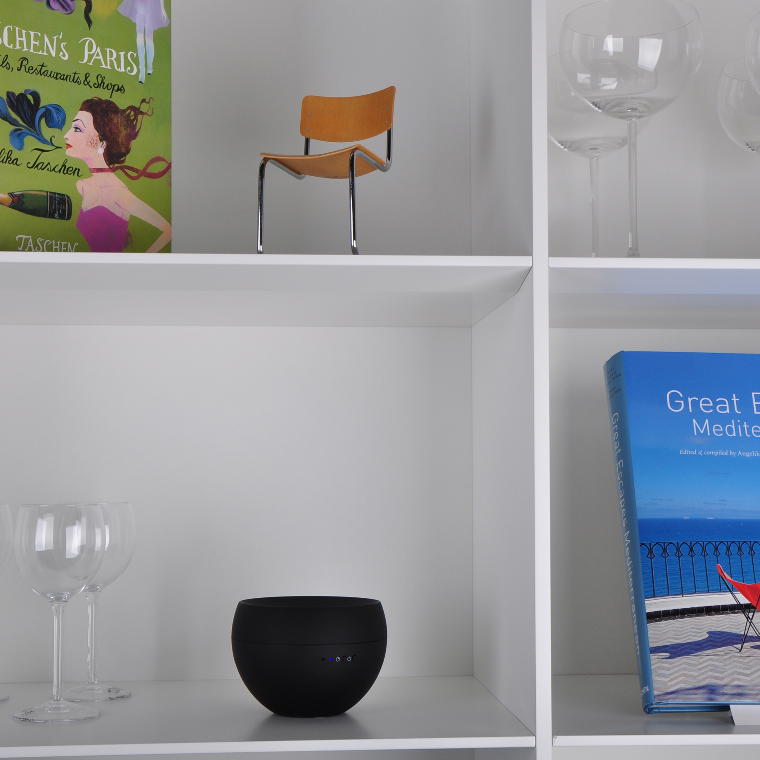 White shelves with books, glasses, and a black speaker.