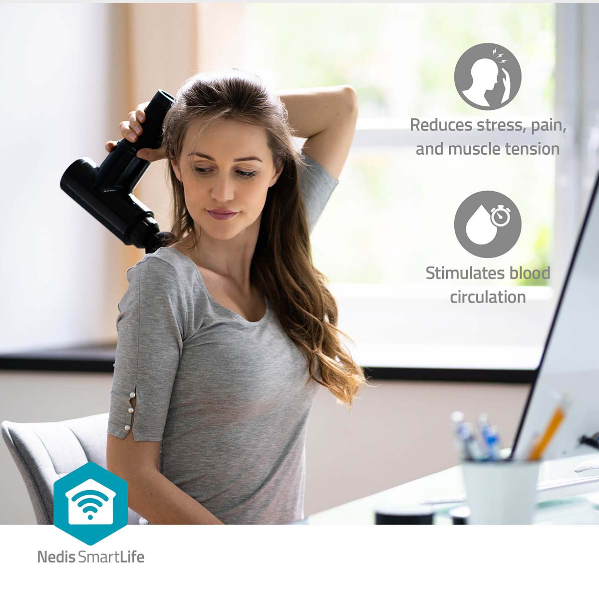 Vrouw met een massagepistool op haar nek. Het is in een kantooromgeving, vlakbij een computer.