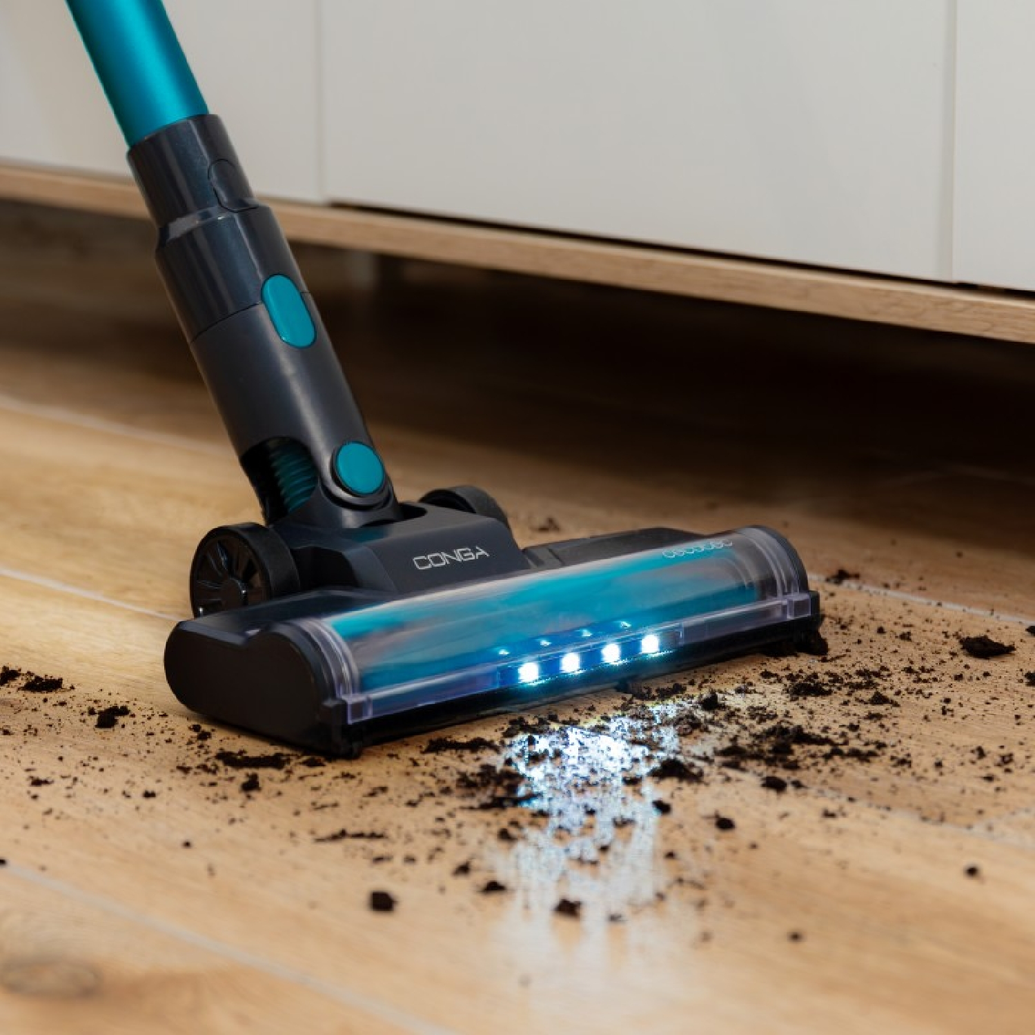 Una testina per aspirapolvere con luci che pulisce lo sporco su un pavimento in legno.