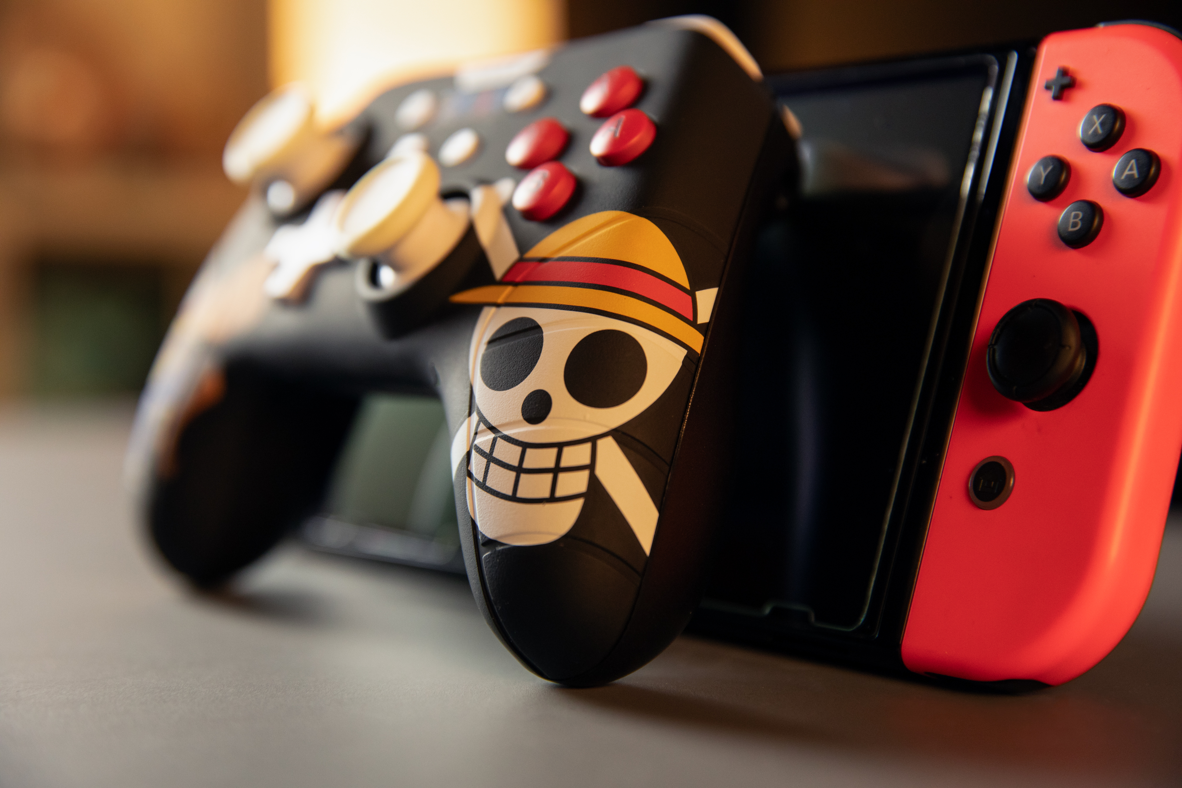 Czarny kontroler do gier z motywem czaszki znajduje się przed czerwoną konsolą Switch.