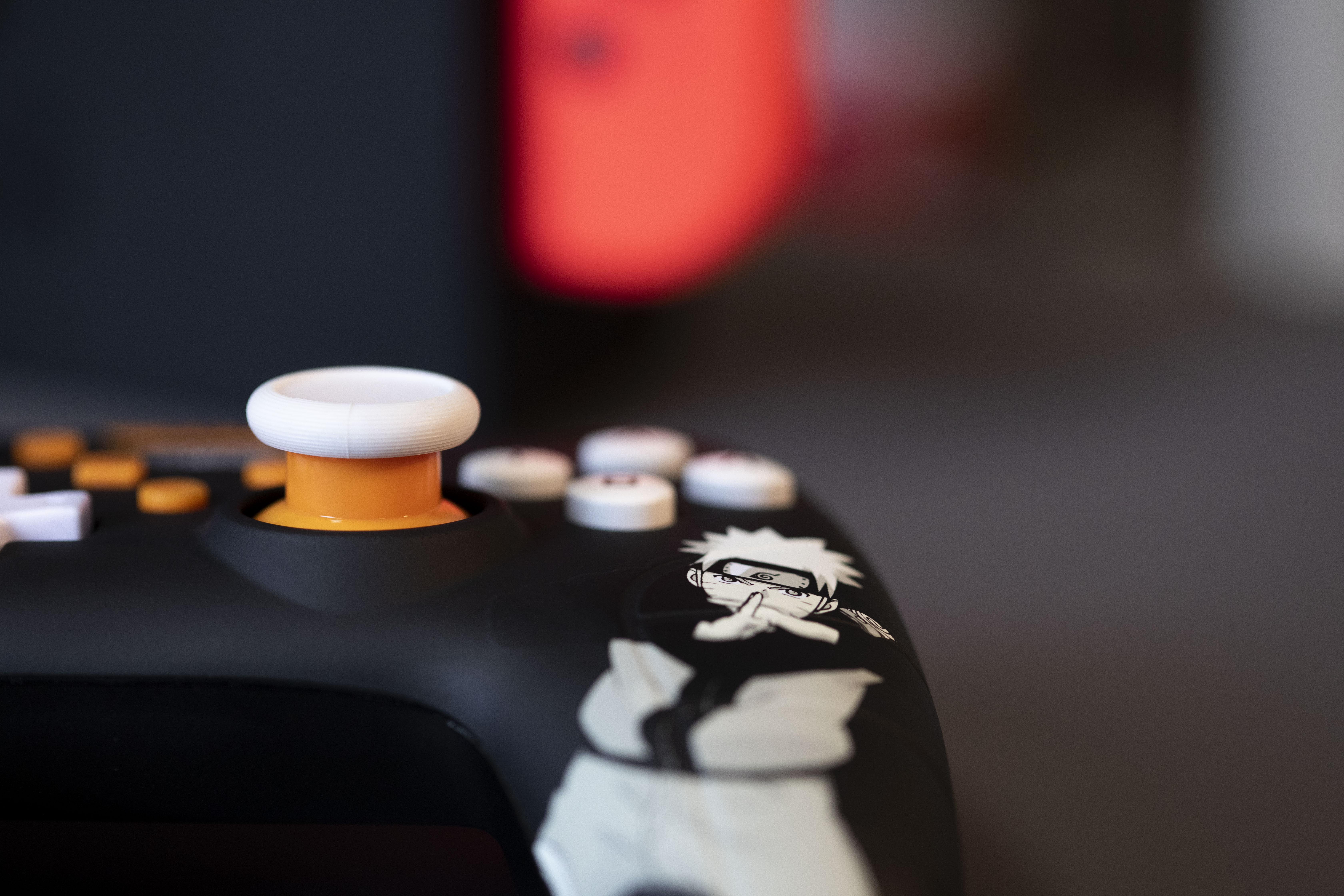 Zbliżenie czarno-pomarańczowego kontrolera do gier wideo z motywem Naruto.