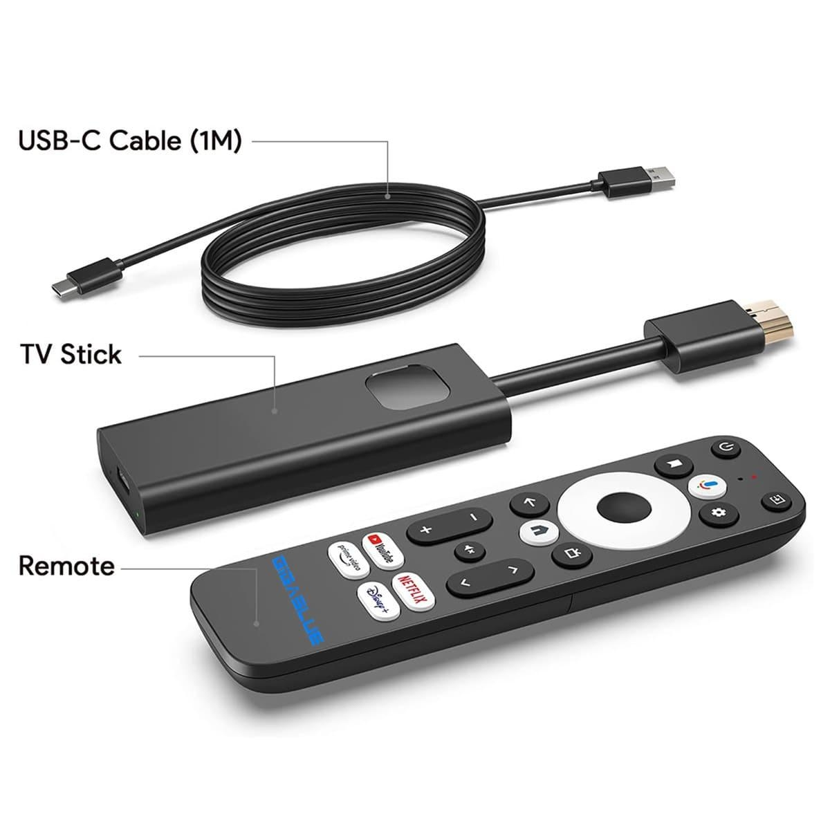 Ein TV-Stick, eine Fernbedienung und ein USB-C-Kabel, die auf einer weißen Oberfläche mit Beschriftungen ausgelegt sind.