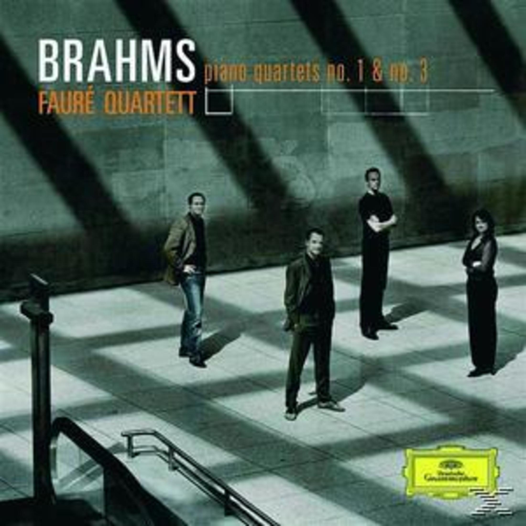 Album cover. Four men in suits standing on a gray surface, Brahms piano quartets on top.