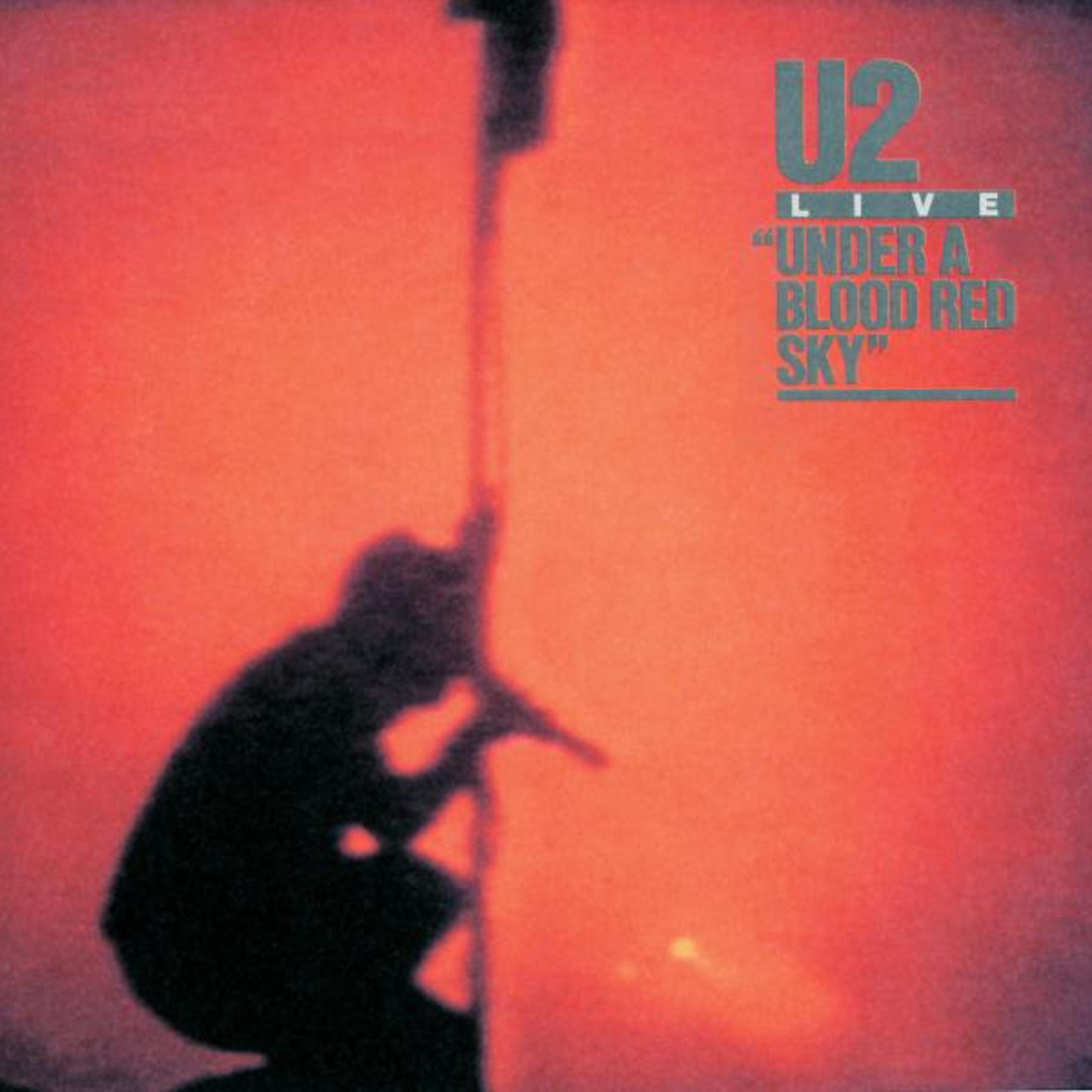 U2 albumhoes. Een silhouet knielt voor een rode hemel met de albumtitel.