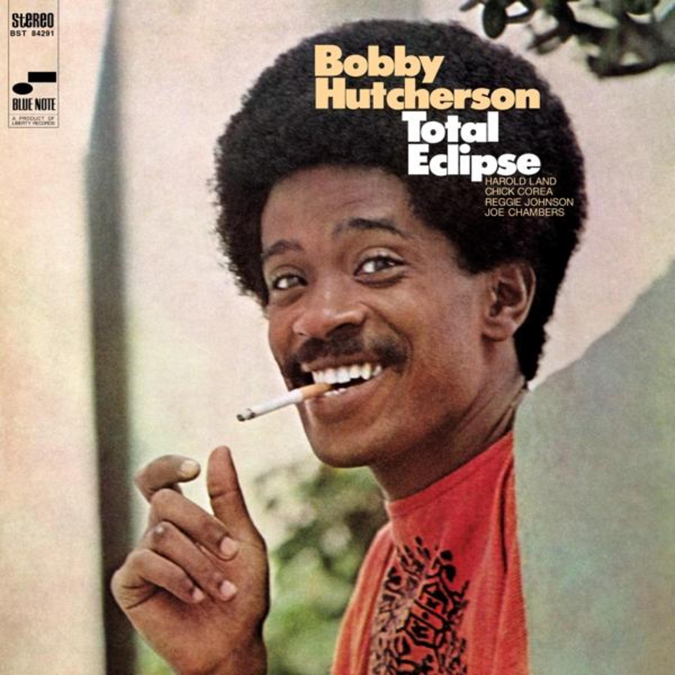 Pochette d'album d'un homme noir souriant fumant une cigarette. Titre 'Total Eclipse'.