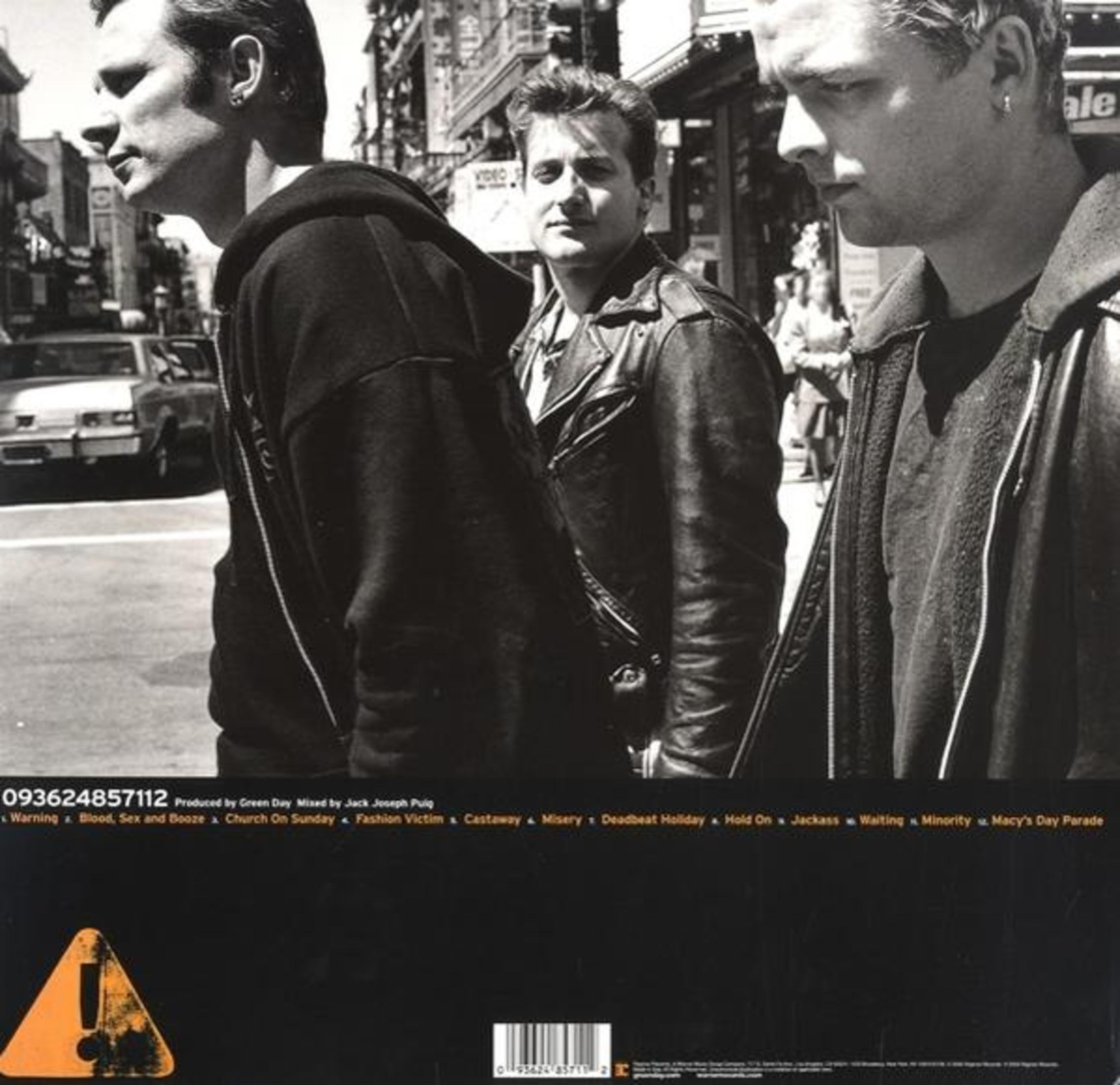 Portada del álbum con tres hombres frente a un edificio, texto en la parte inferior y superior.