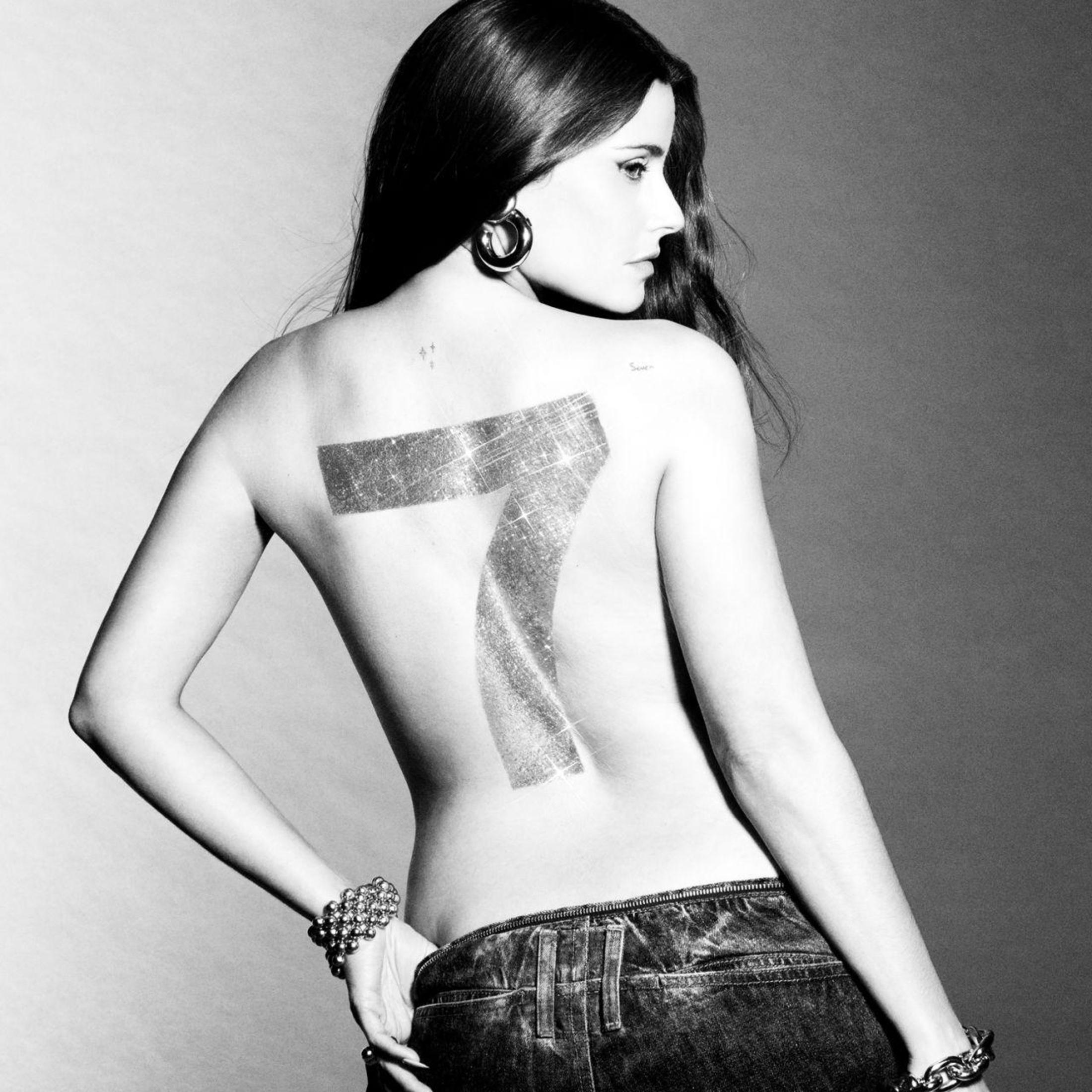 Mujer de espaldas a la cámara, tatuaje de un siete en la espalda.