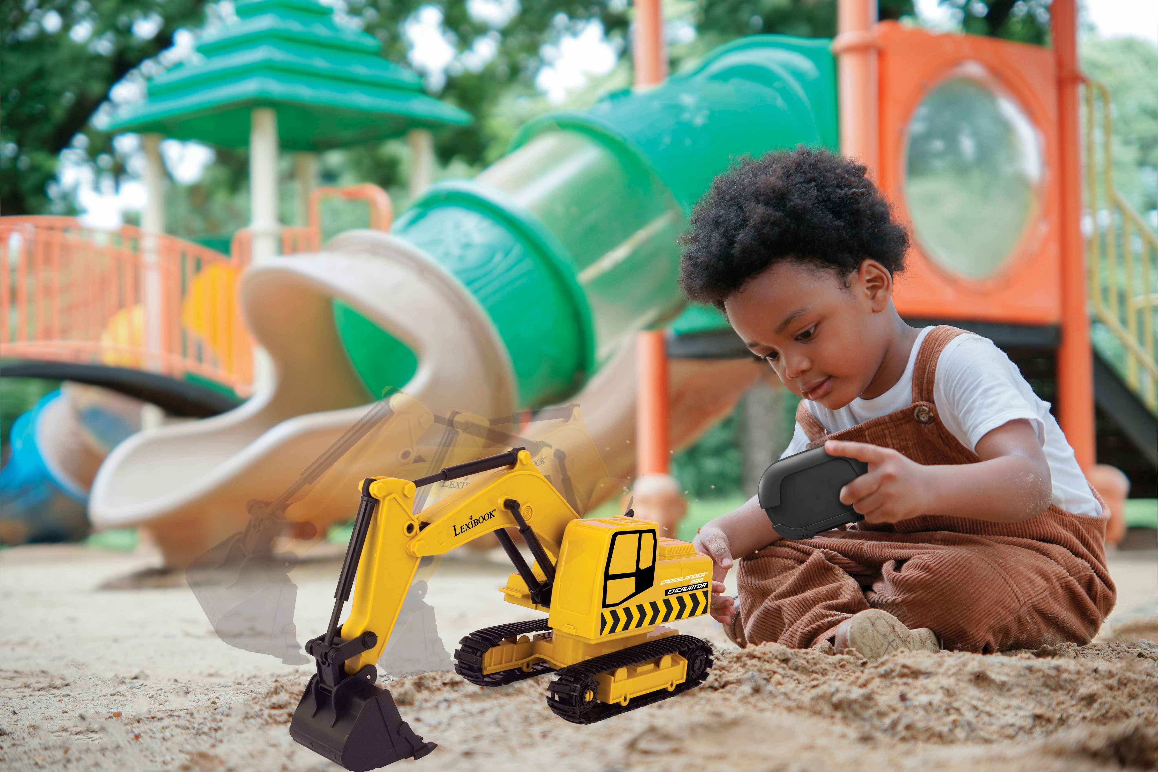 Un niño juega con una excavadora de juguete amarilla en un arenero en un parque infantil.