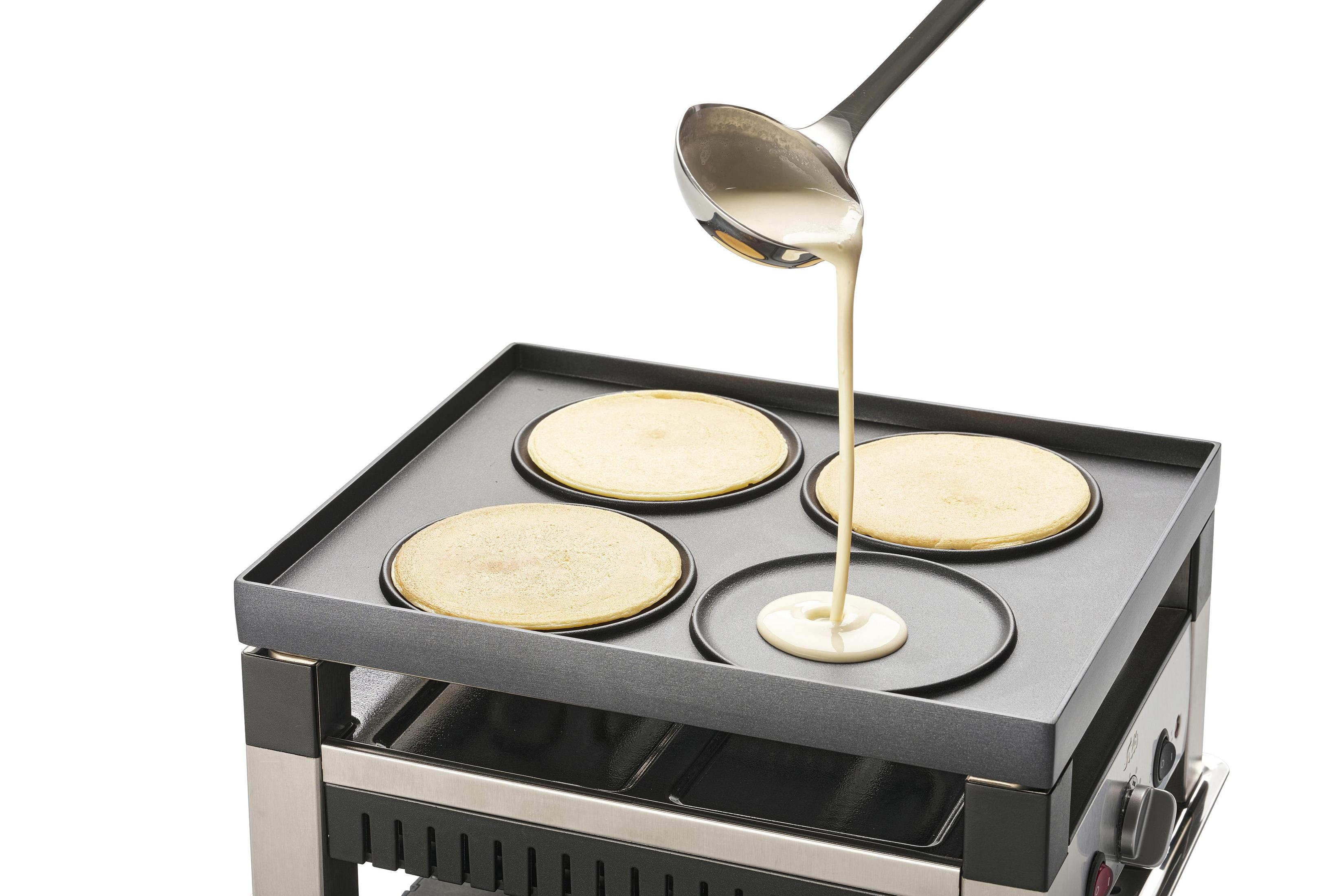 Pfannkuchenteig wird auf eine Grillplatte gegossen, auf der bereits Pfannkuchen backen.