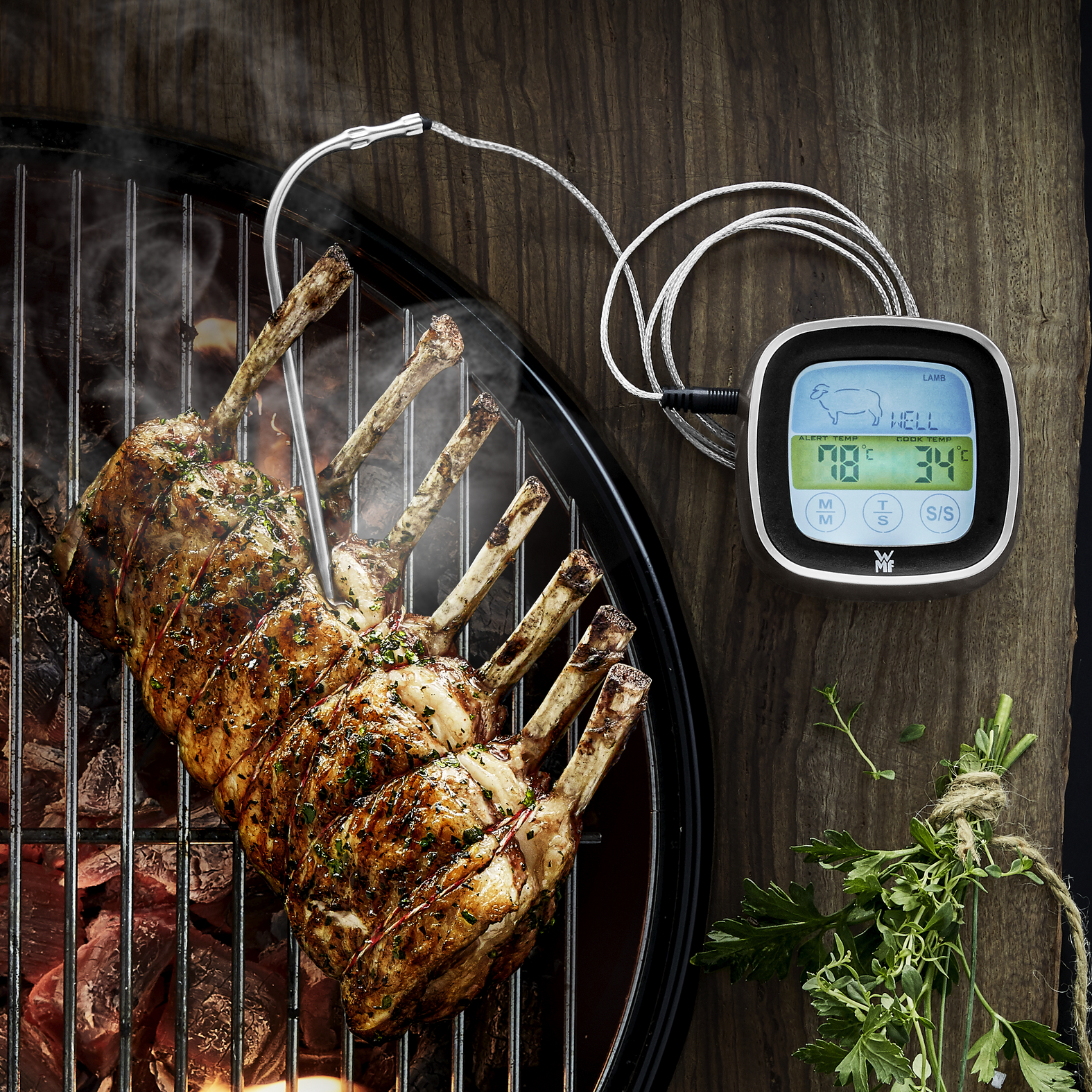 Lammkarree auf dem Grill mit Thermometer und Digitalanzeige. Holz-Hintergrund.