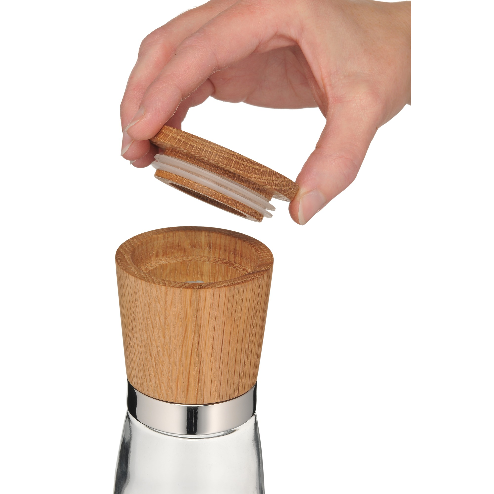 Eine Hand hält einen Holzdeckel über einer Glasflasche. An der Flasche befindet sich ein silberner Ring.