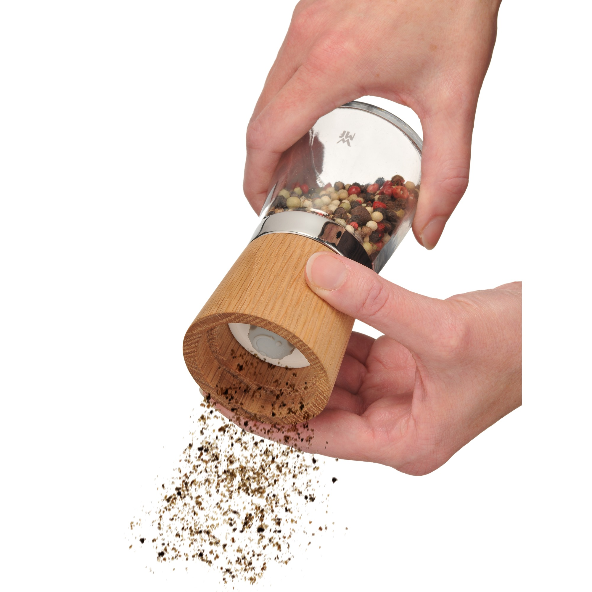 Hände, die Pfeffer mahlen. Sie halten eine hölzerne Pfeffermühle über einer weißen Oberfläche.