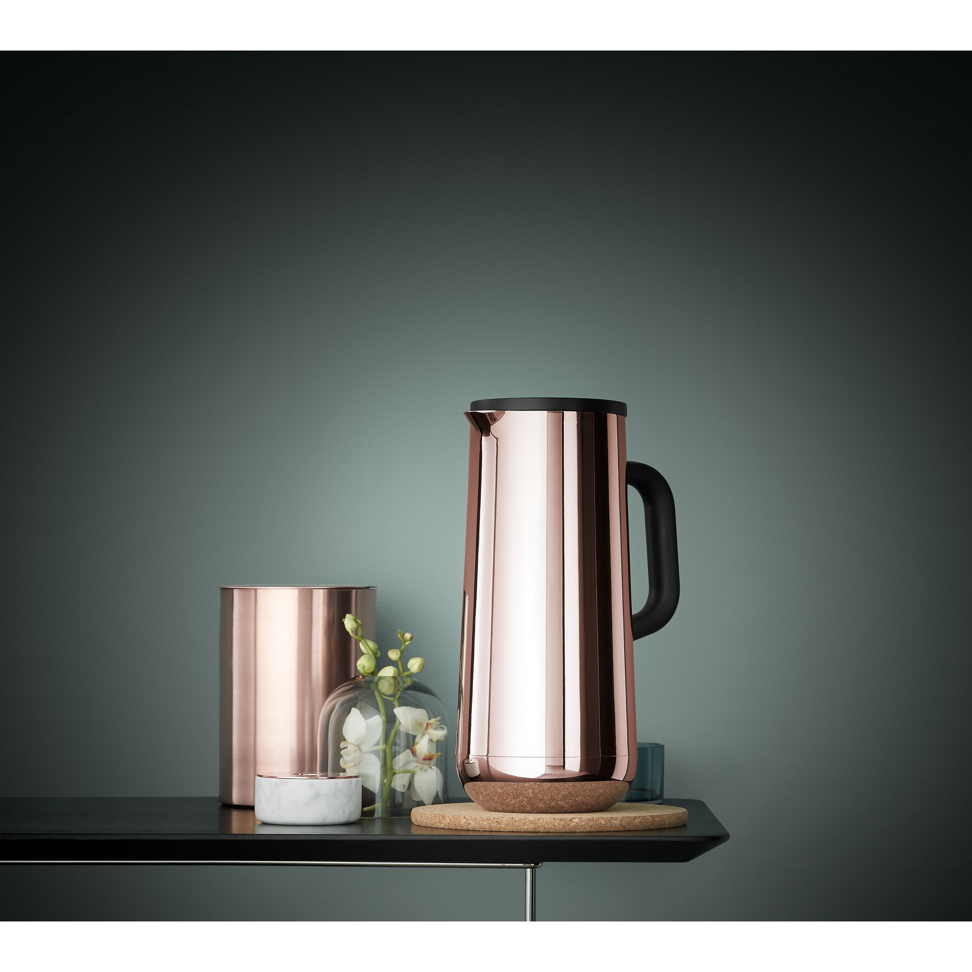 Carafe thermique or rose et autres éléments décoratifs sur une table.