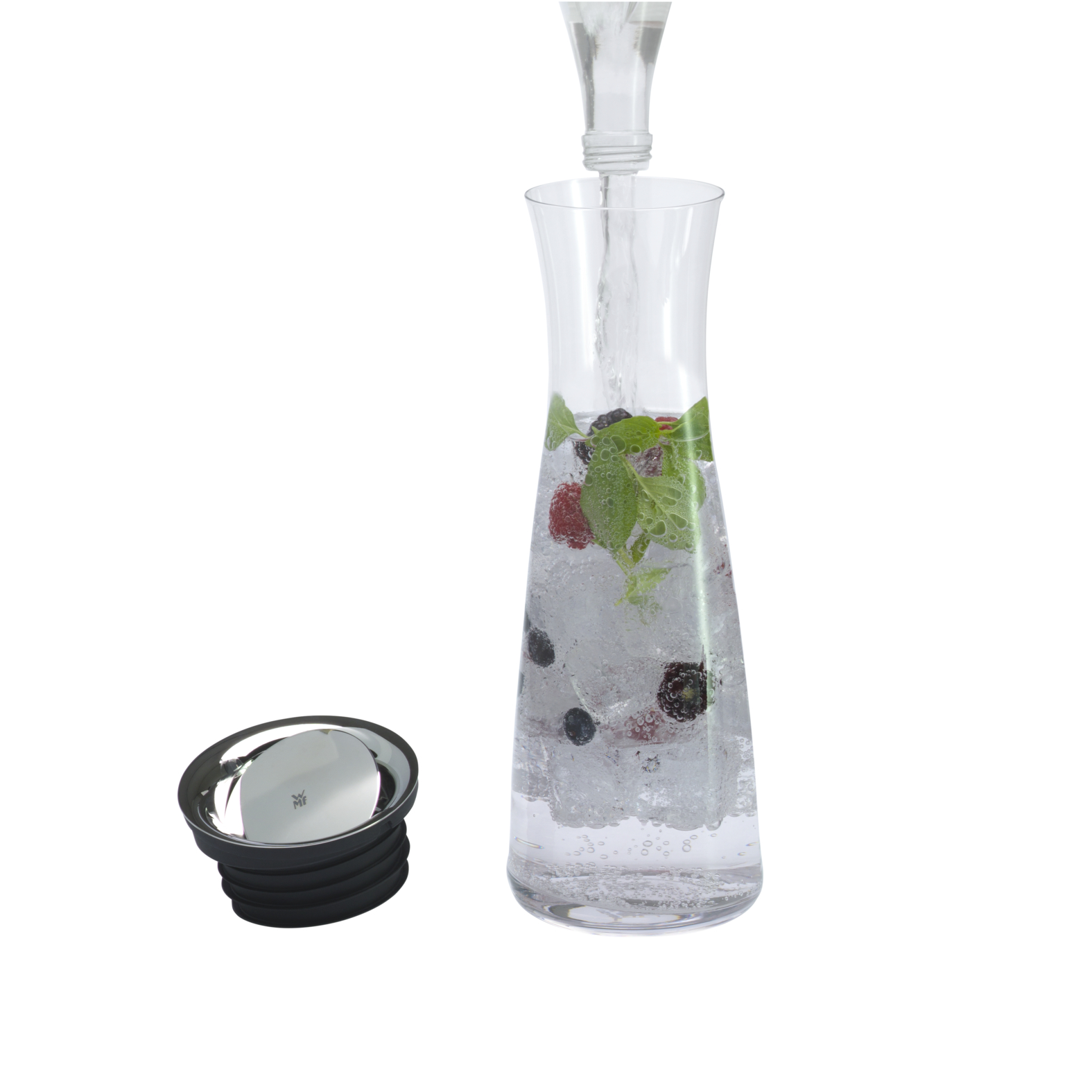 Glaskaraffe mit Wasser, Minze, Beeren. Ein Silberdeckel daneben. Weißer Hintergrund.