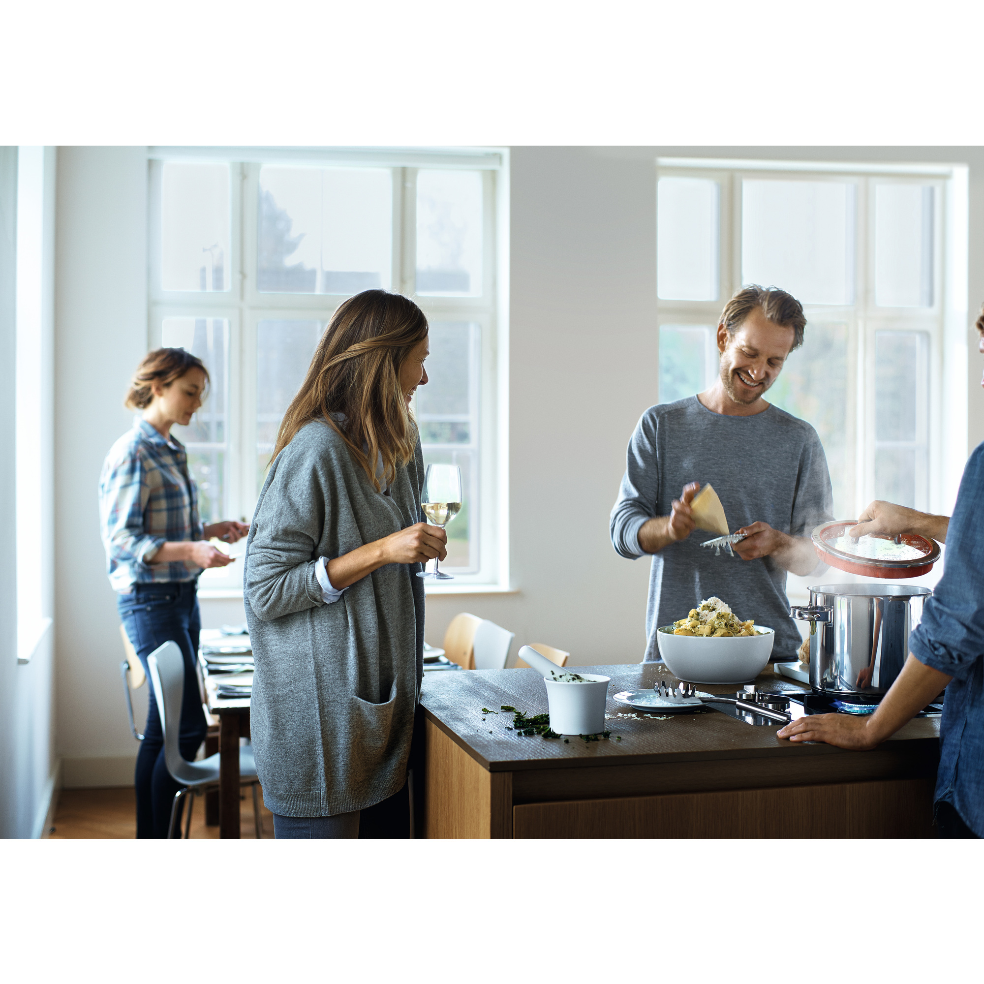 Eine Gruppe von Leuten, die Pasta kochen, mit einer Person, die Käse über eine Schüssel reibt.