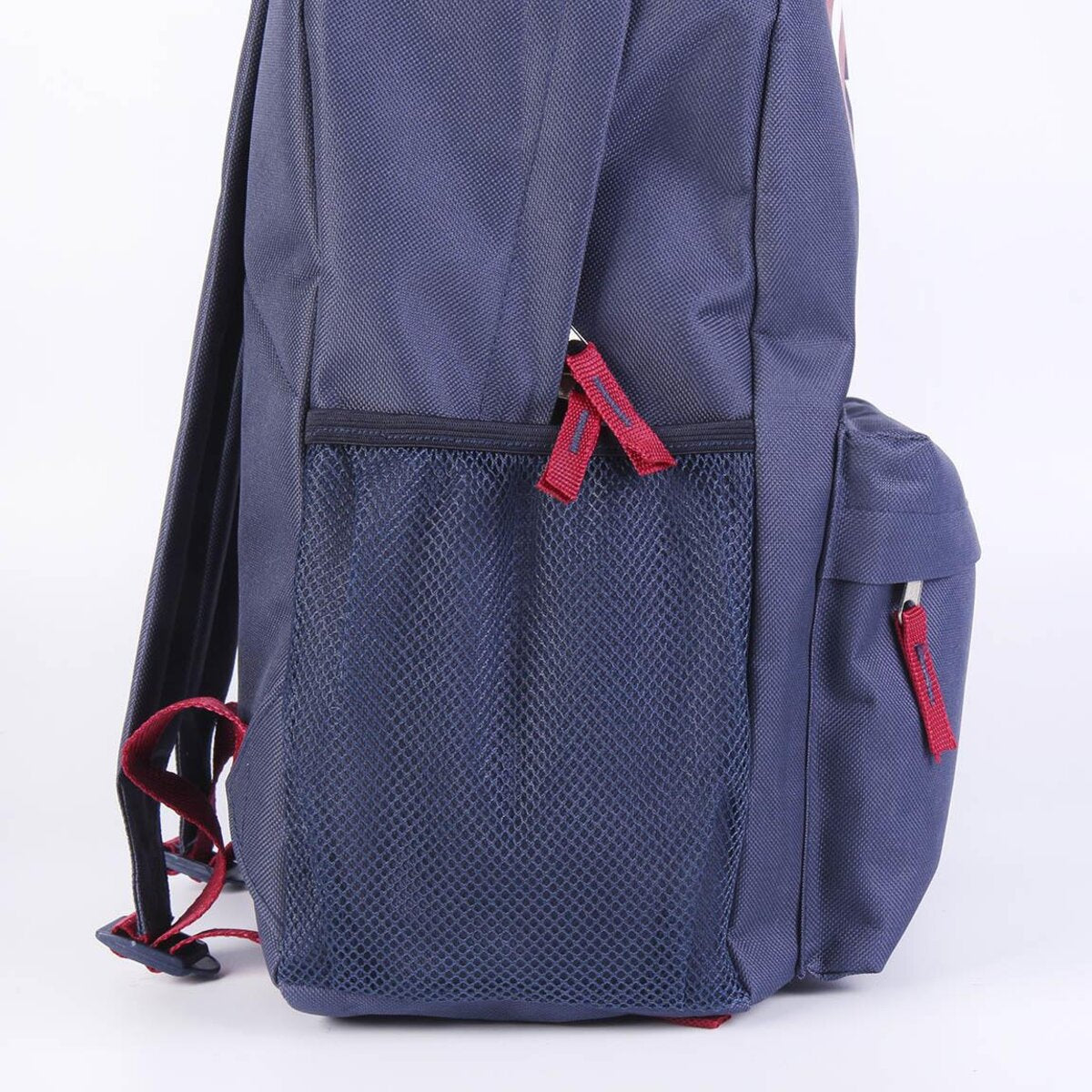 Una mochila azul marino se ve de lado. Tiene un bolsillo de malla, detalles en rojo y un pequeño bolsillo lateral con cremallera roja.
