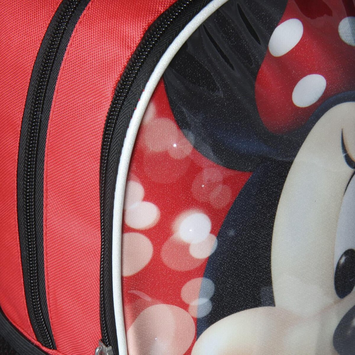Una mochila roja con cremalleras negras y un diseño de Minnie Mouse. El diseño incluye lunares rojos y la cara de Minnie.