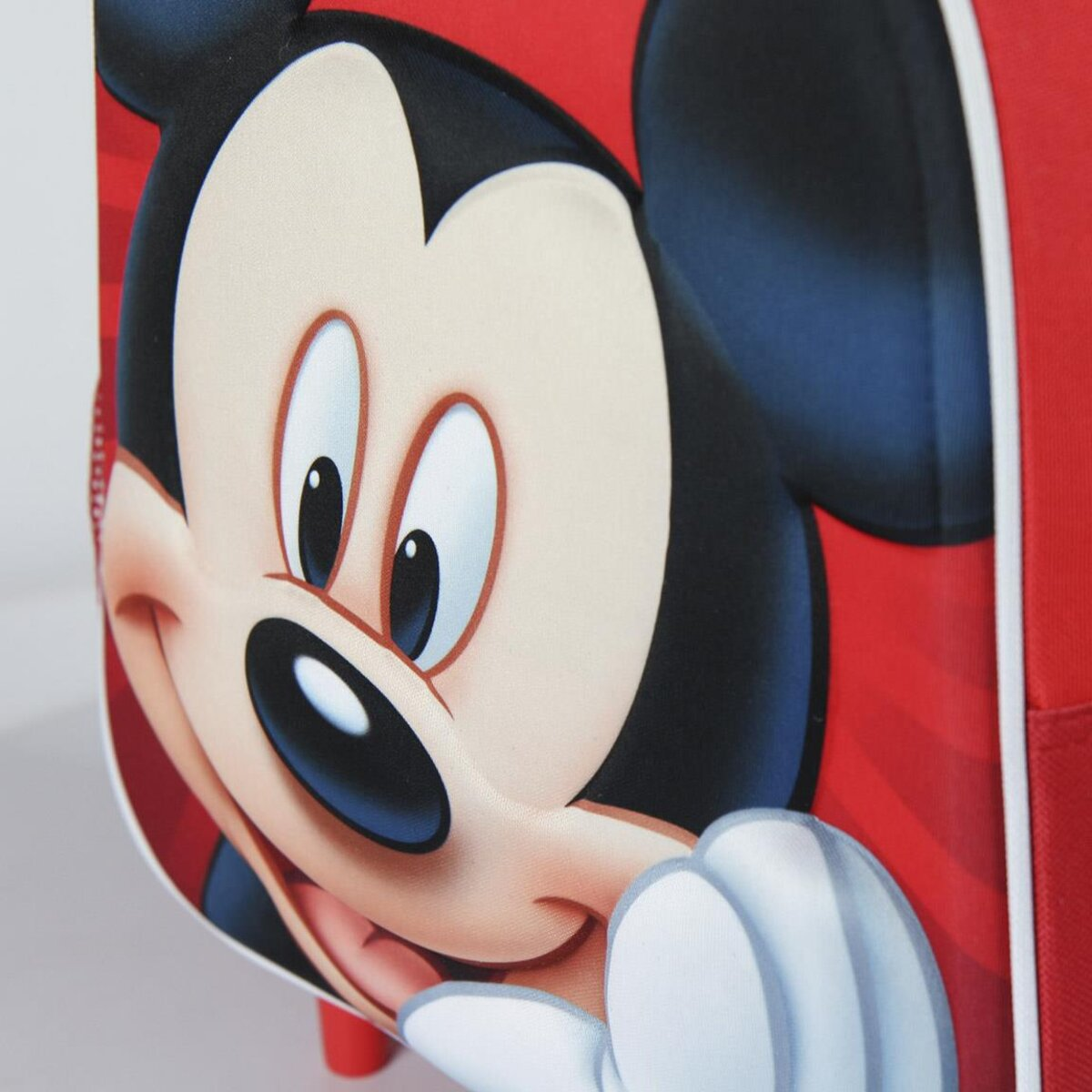 Primer plano de la cara de Mickey Mouse en una maleta roja, mostrando su rostro sonriente.