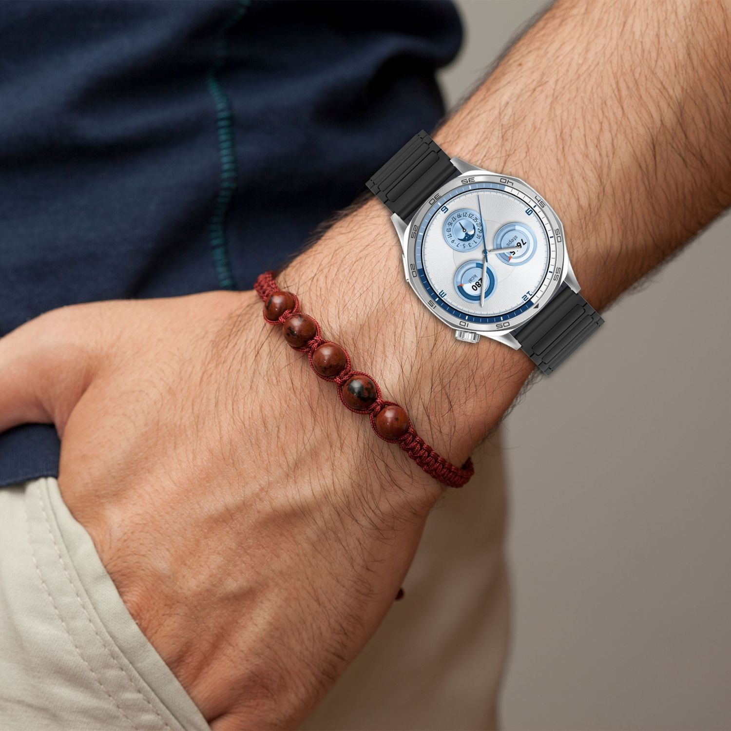 Eine Armbanduhr und ein Armband werden am Handgelenk einer Person getragen.