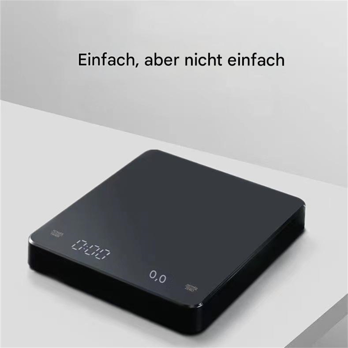 Schwarze Digitalwaage mit beleuchtetem Display auf weißer Oberfläche, Text oben.
