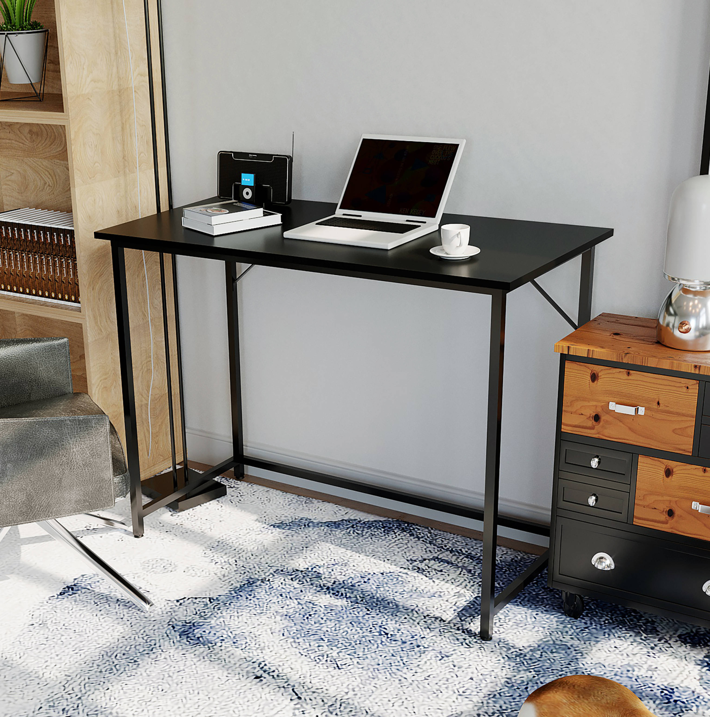 Zwart bureau met een laptop, lamp en andere items op een tapijt met een blauw patroon.