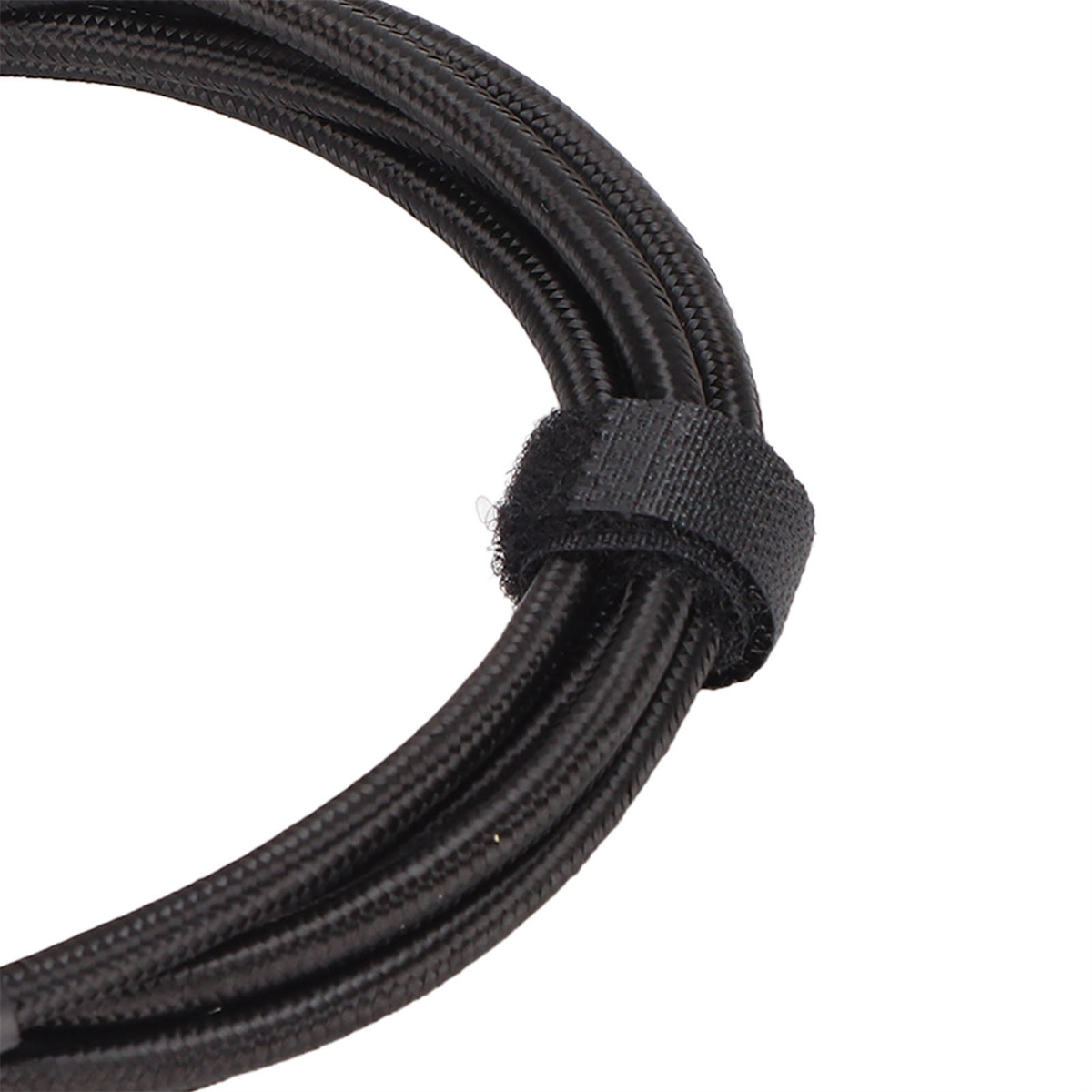 Ein schwarzes Kabel, das mit einem Klettverschluss umwickelt ist. Das Kabel ist dick und strukturiert.