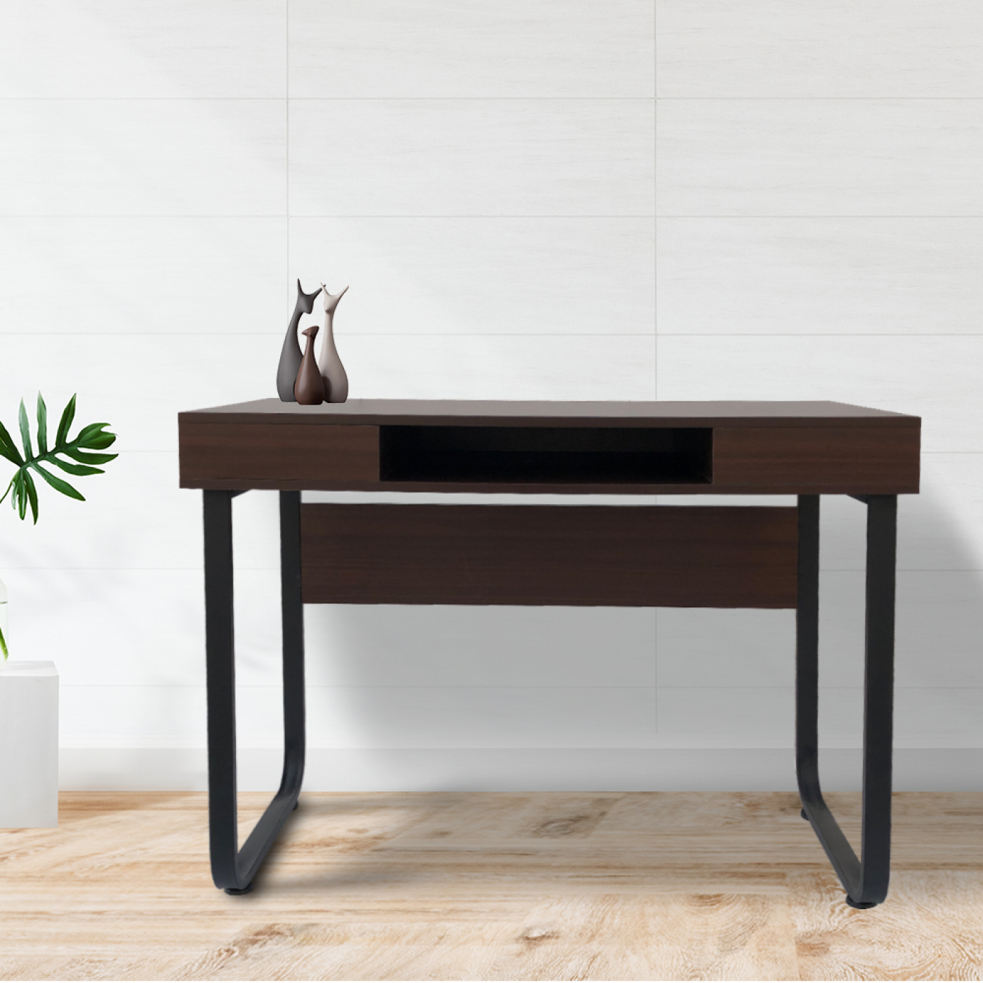 Ein dunkler Holzschreibtisch mit schwarzen Metallbeinen, mit drei kleinen Skulpturen darauf.