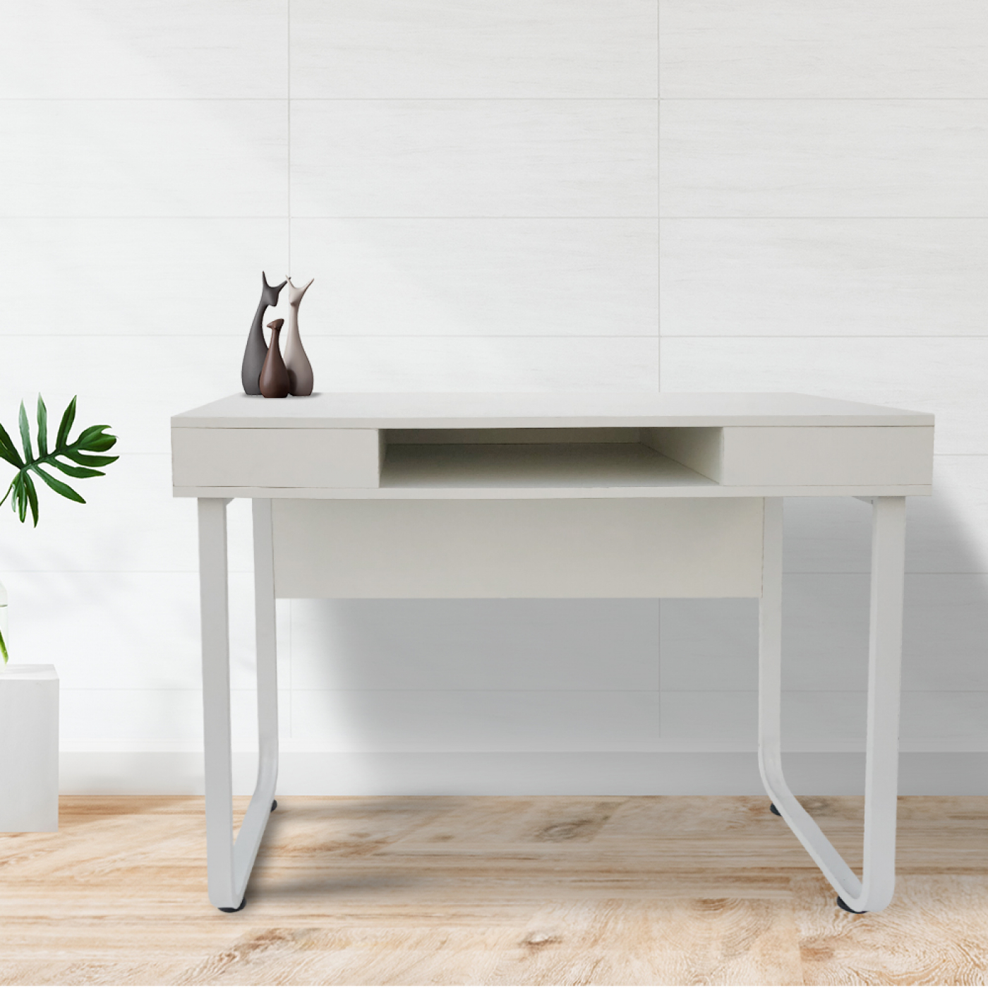 Witte bureau met drie kleine beeldjes erop.