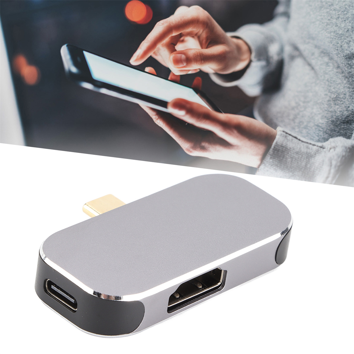 Silberner USB-C-Hub mit Anschlüssen. Telefonbildschirm im Hintergrund. Graue Oberfläche.