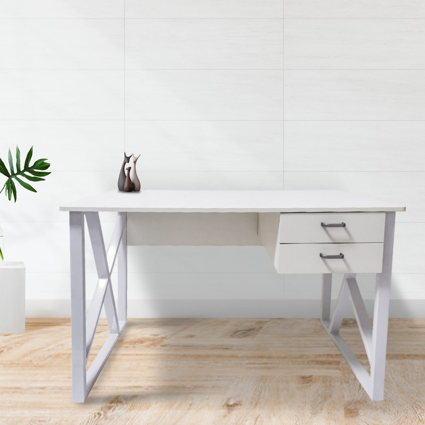 Een wit bureau met twee lades, twee kleine beelden en een plant. Achtergrond: een witte tegelmuur.