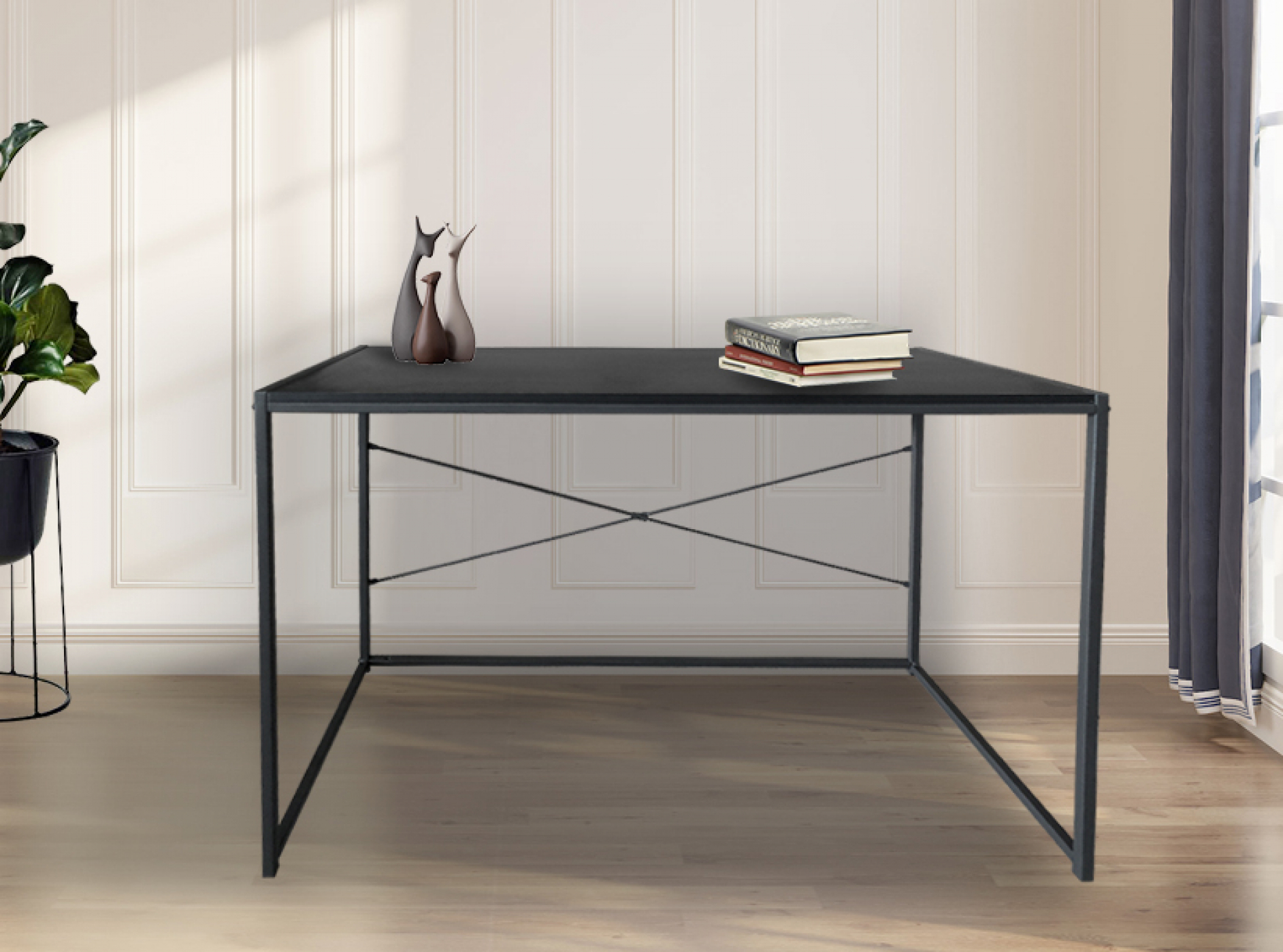 Een zwart metalen bureau met een zwart blad, met boeken en vazen. Het staat tegen een witte muur. De achtergrond is licht.