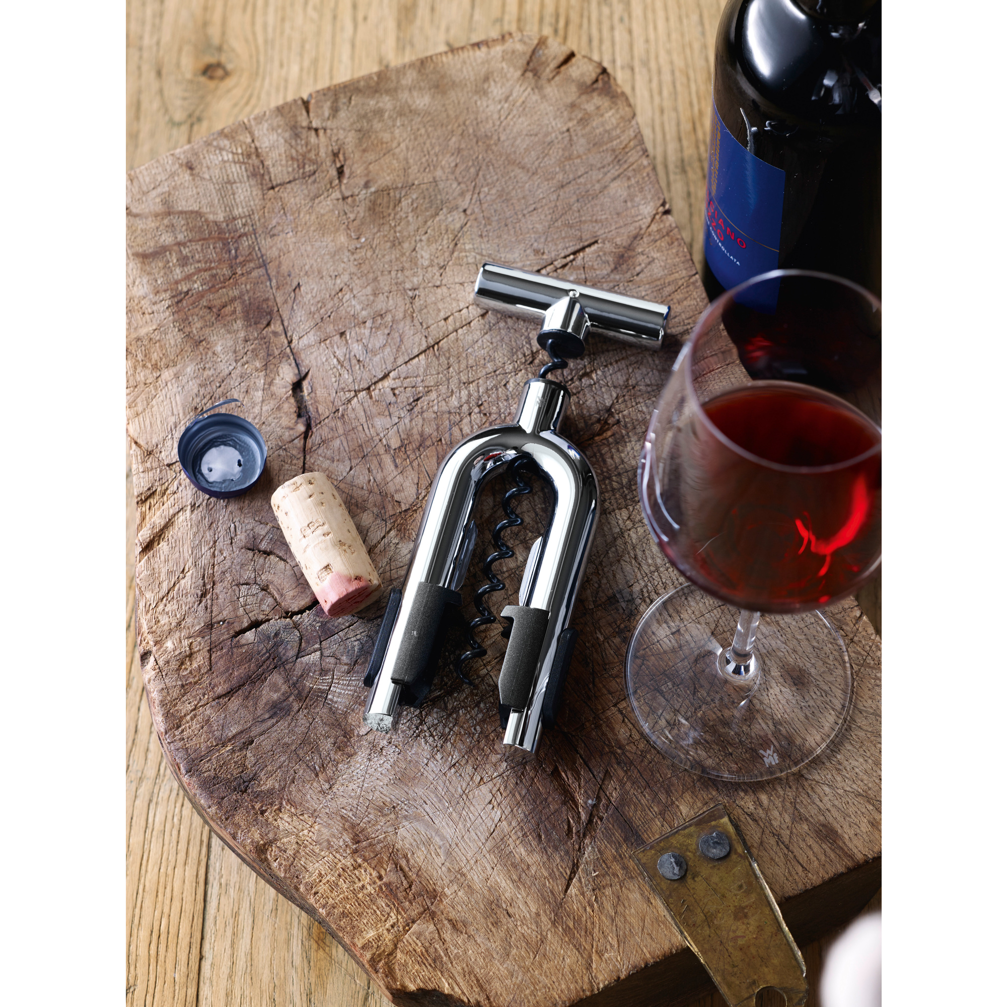 Korkenzieher auf Holz mit Weinglas, Flasche, Korken und Kappe.